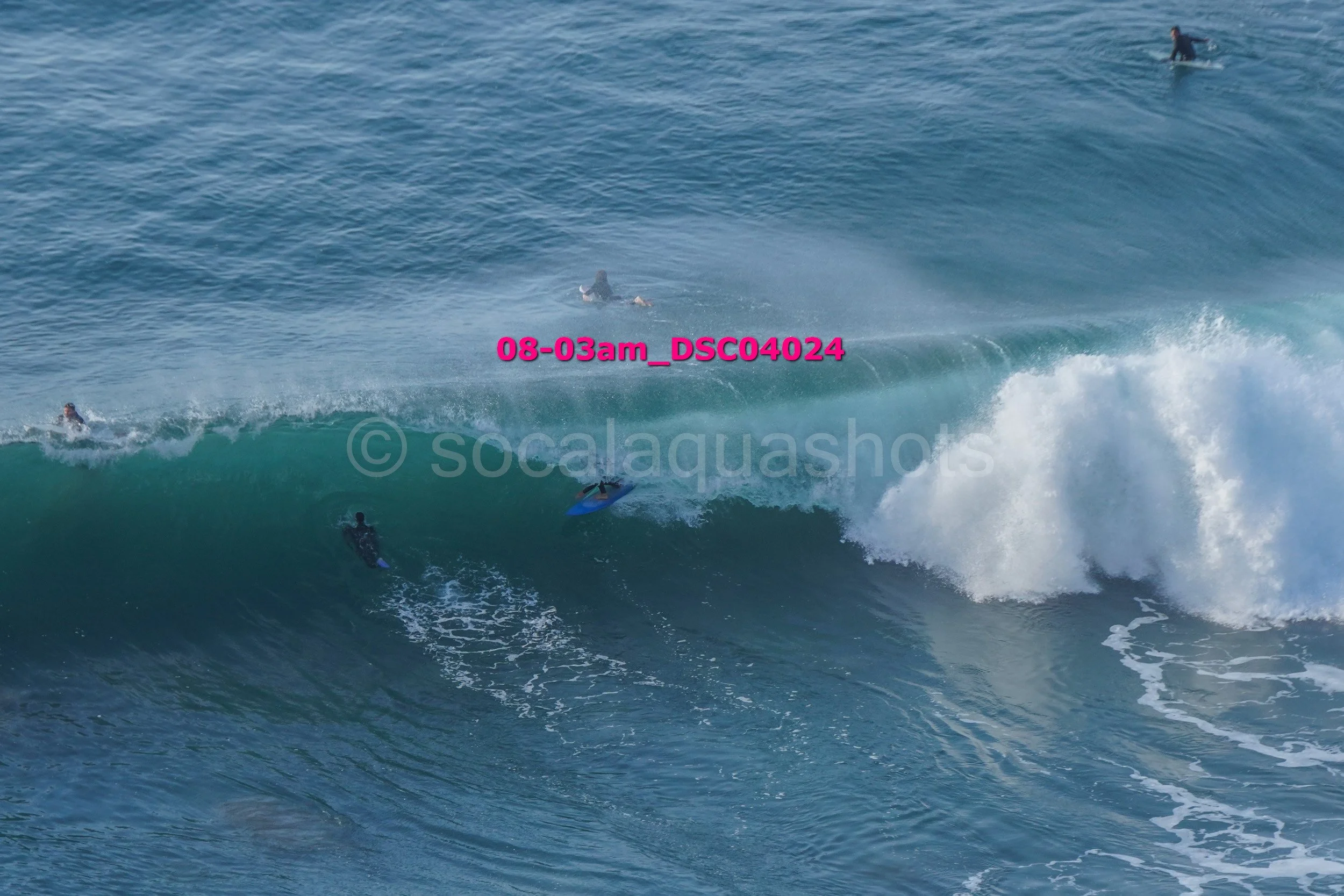 Surfers riding and paddling on ocean waves.