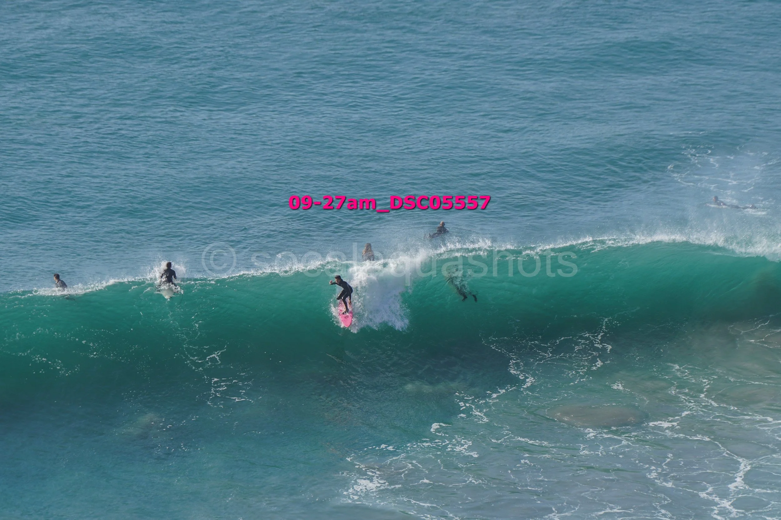 Multiple people surfing a large wave at the beach.