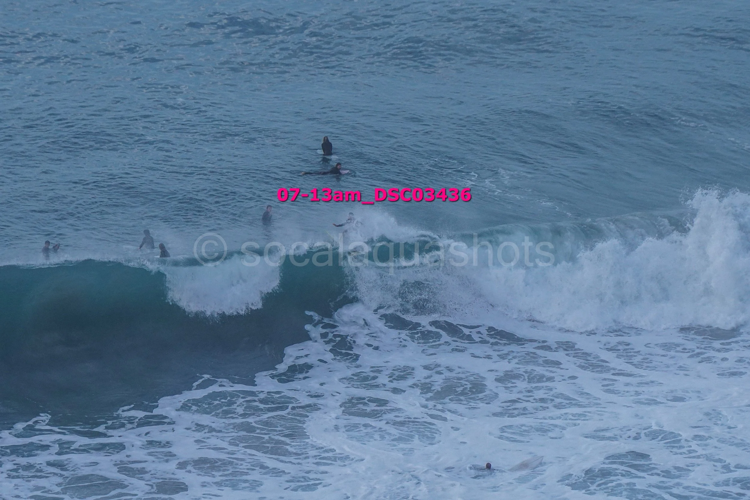 People surfing in the ocean with waves and some swimmers nearby.