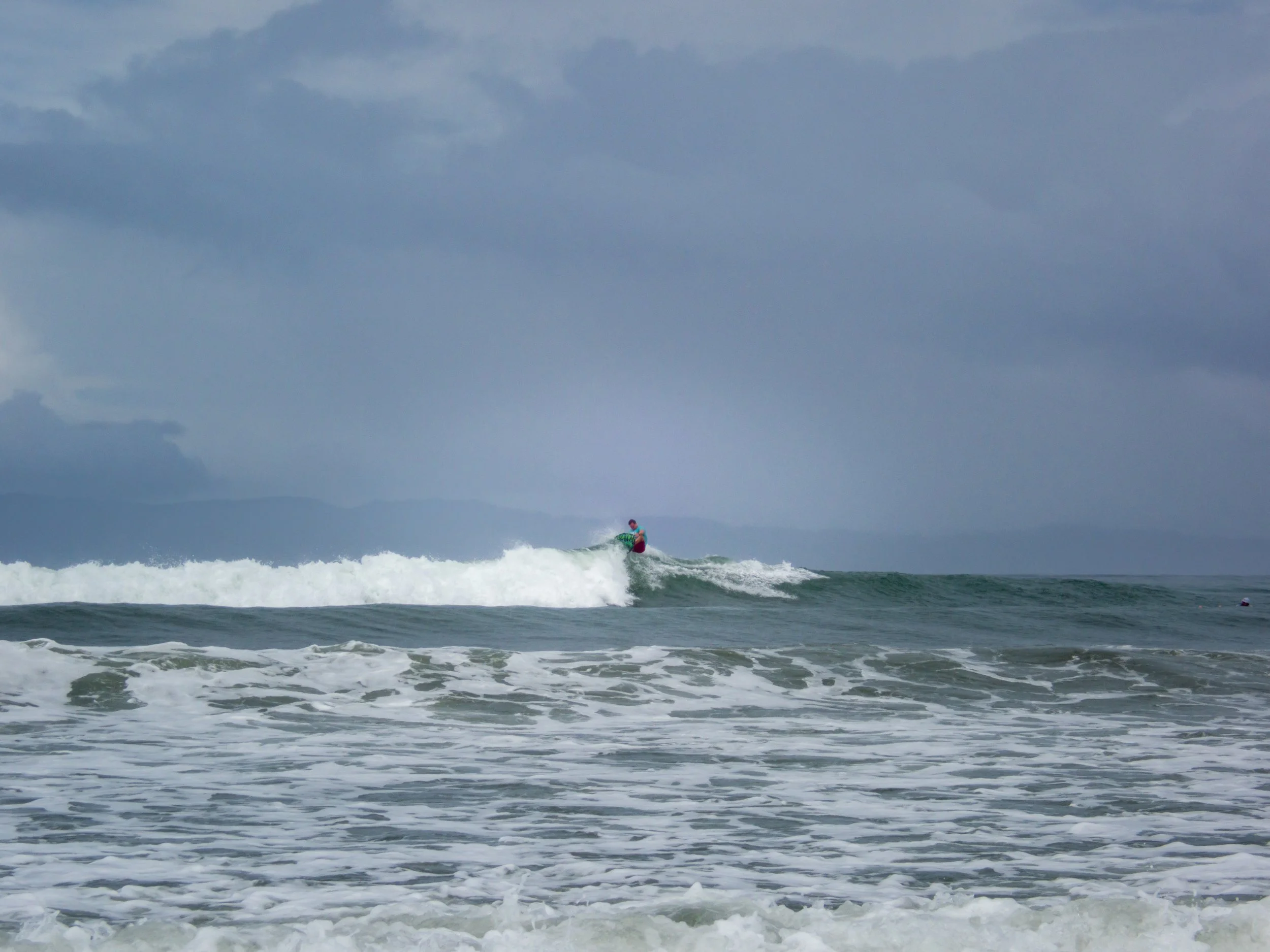 person surfing on ocean waves under cloudy sky