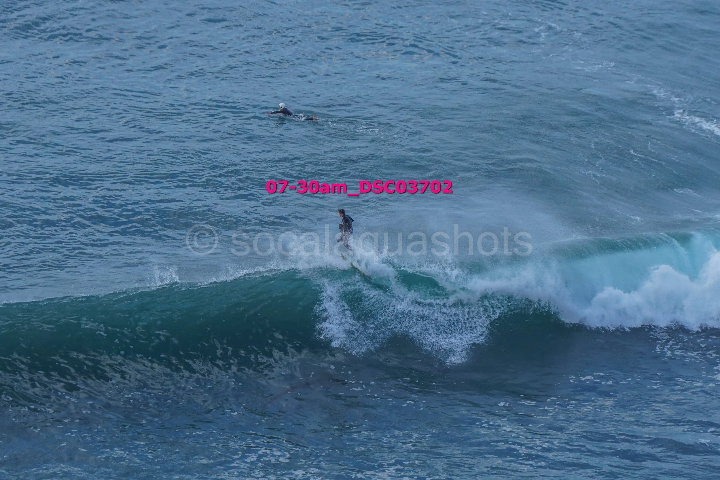 A person standing on a surfboard riding a wave in the ocean during early morning.