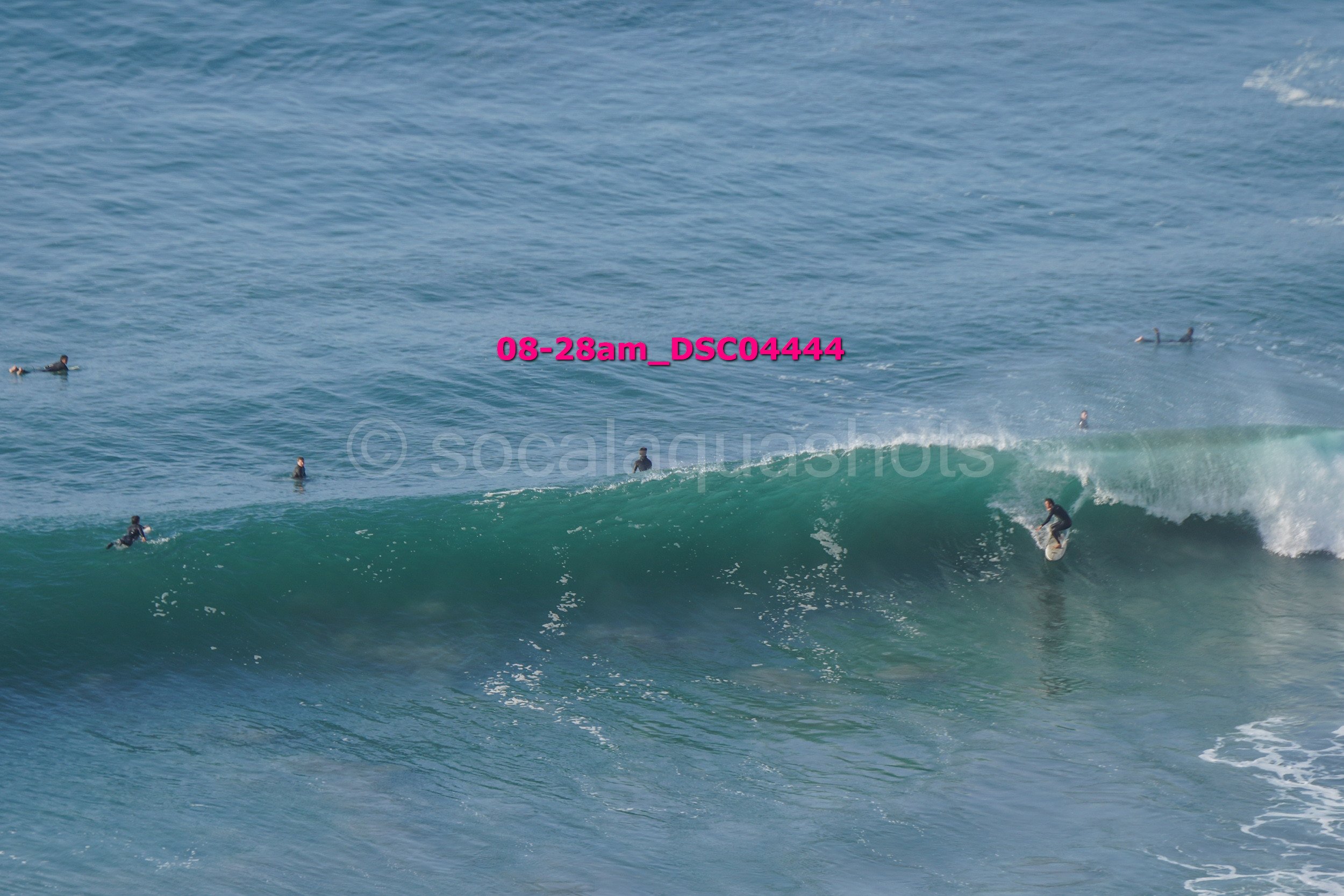 A surfer riding a wave with several surfers in the water around him.