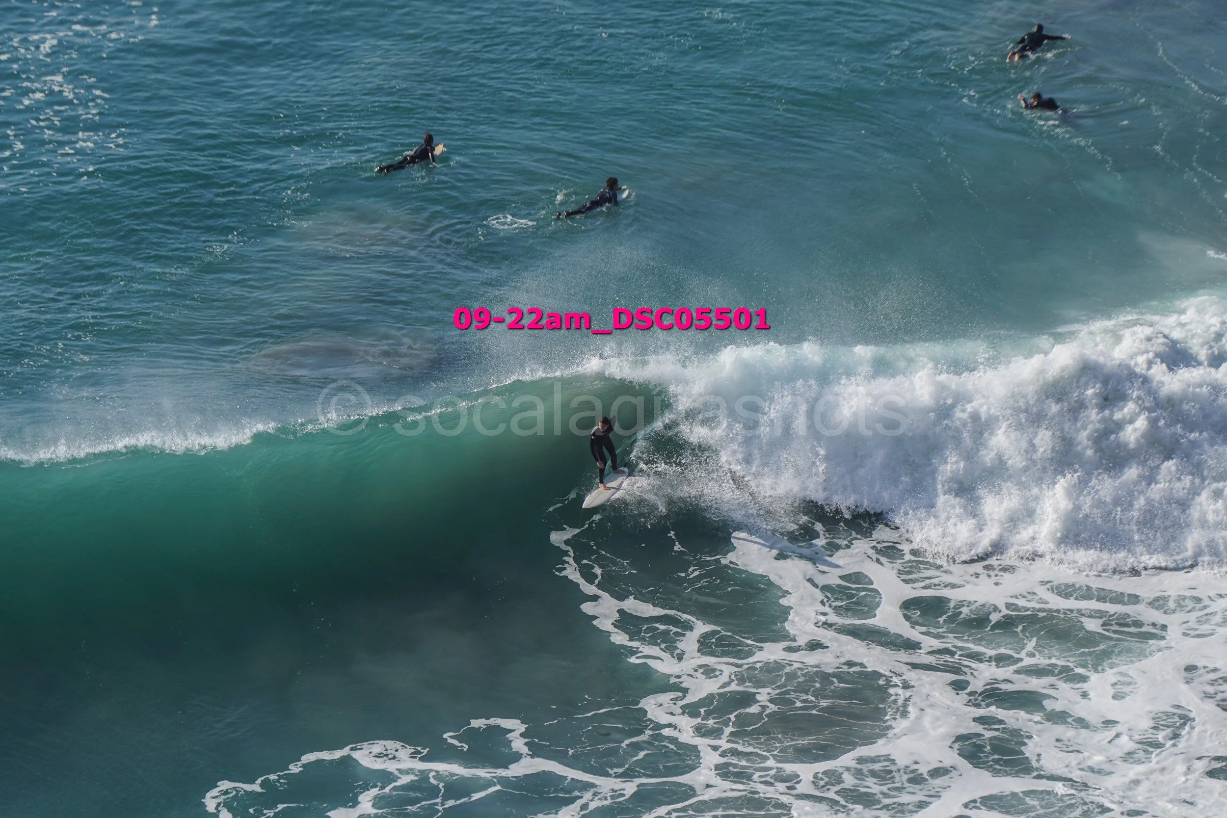 A surfer riding a wave with several surfers in the water in the background.