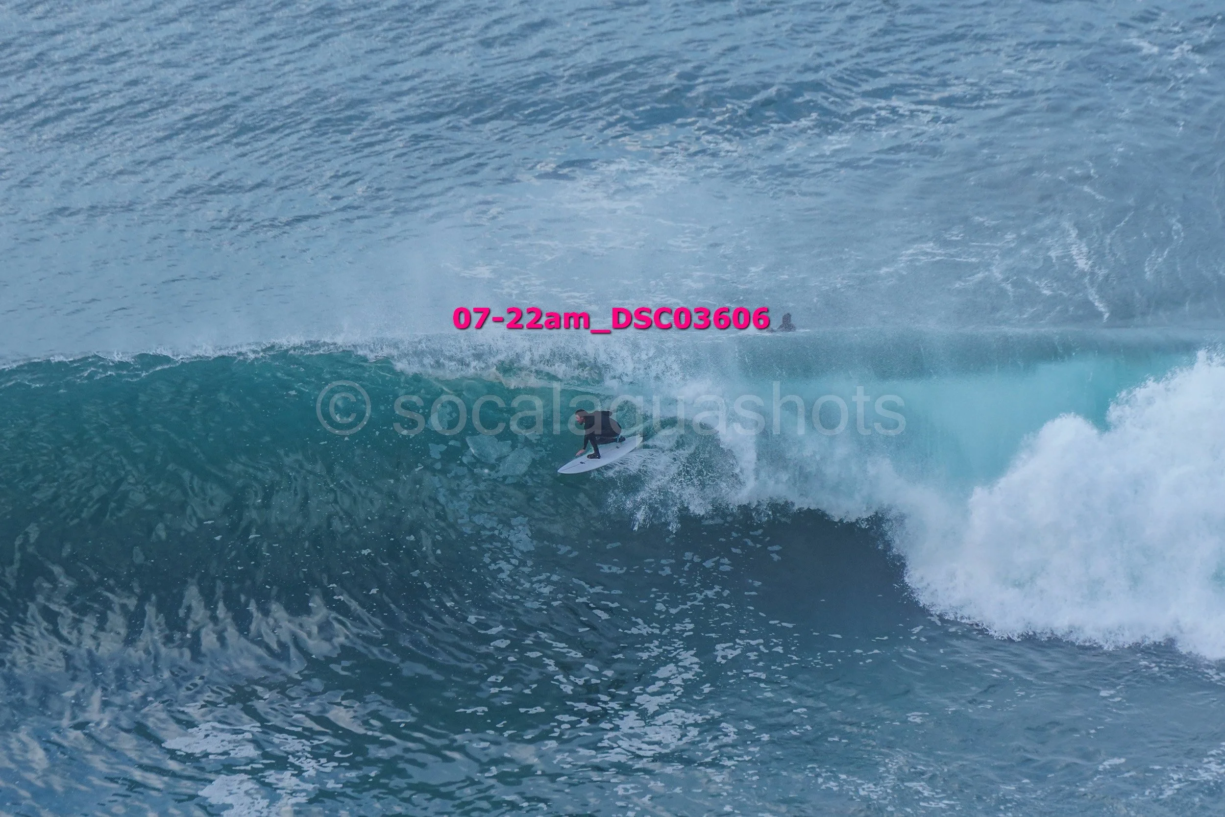 A person surfing on a large ocean wave during daylight.