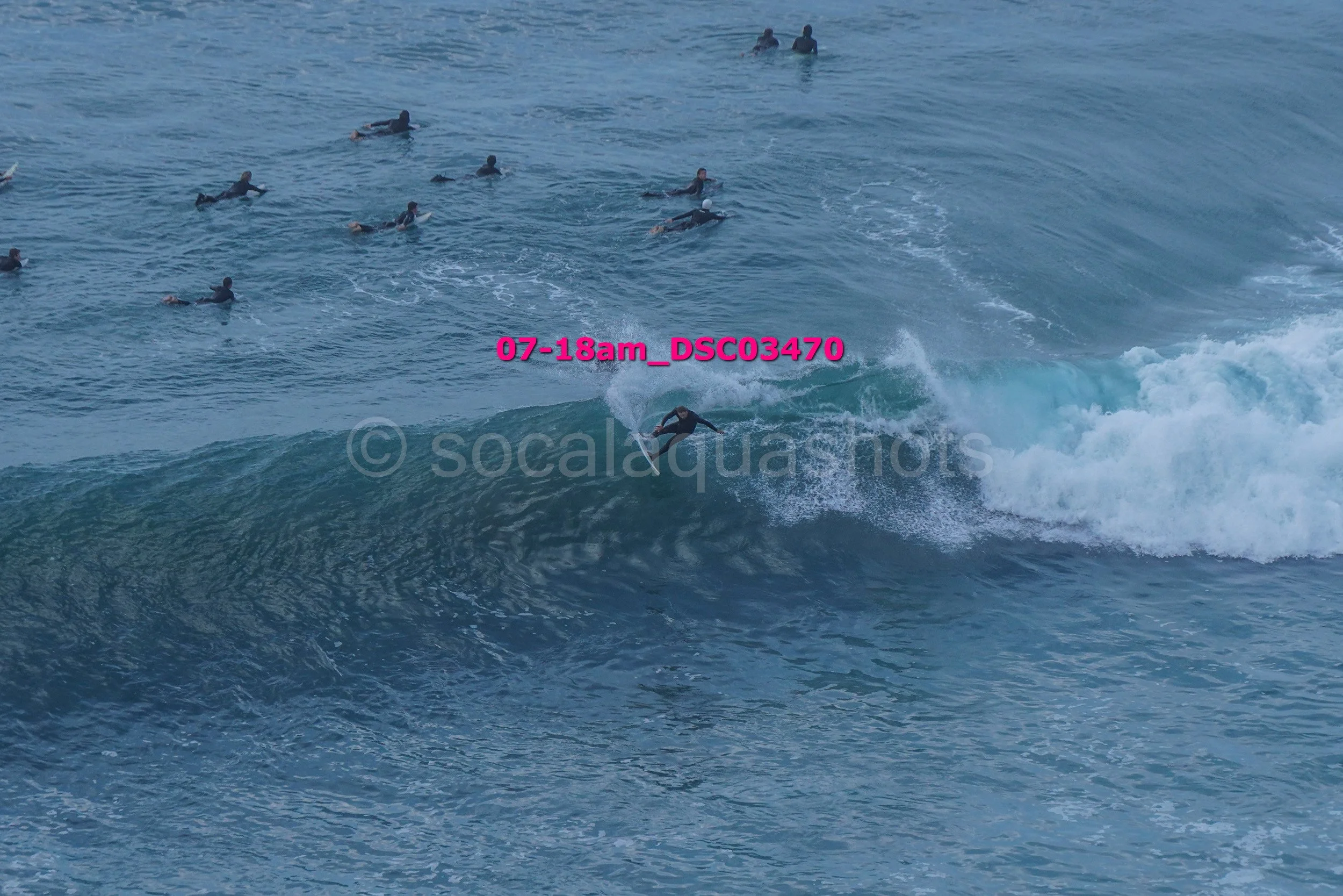 A group of people swimming in the ocean, with one person surfing on a wave.