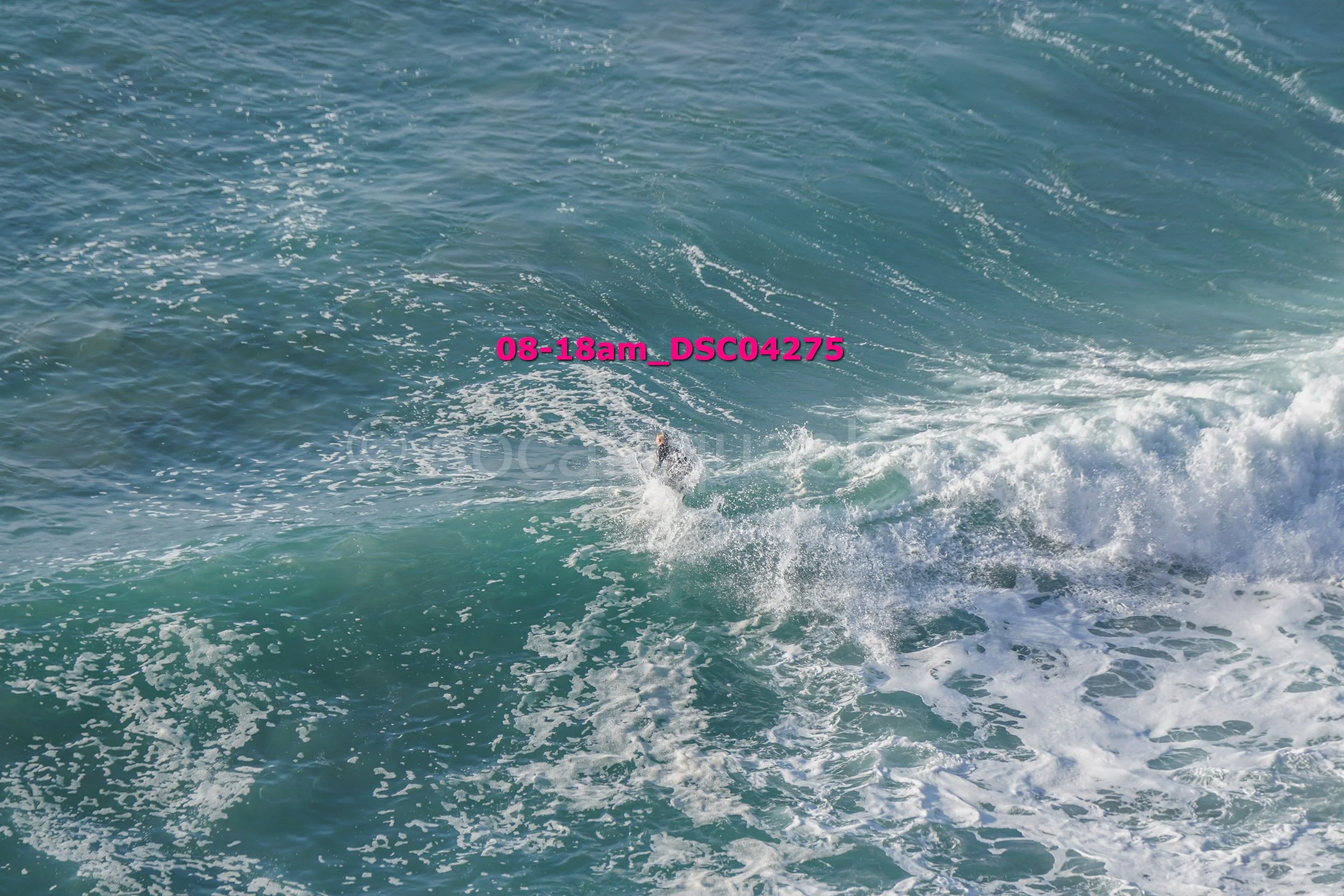 A person surfing on a large blue wave in the ocean.