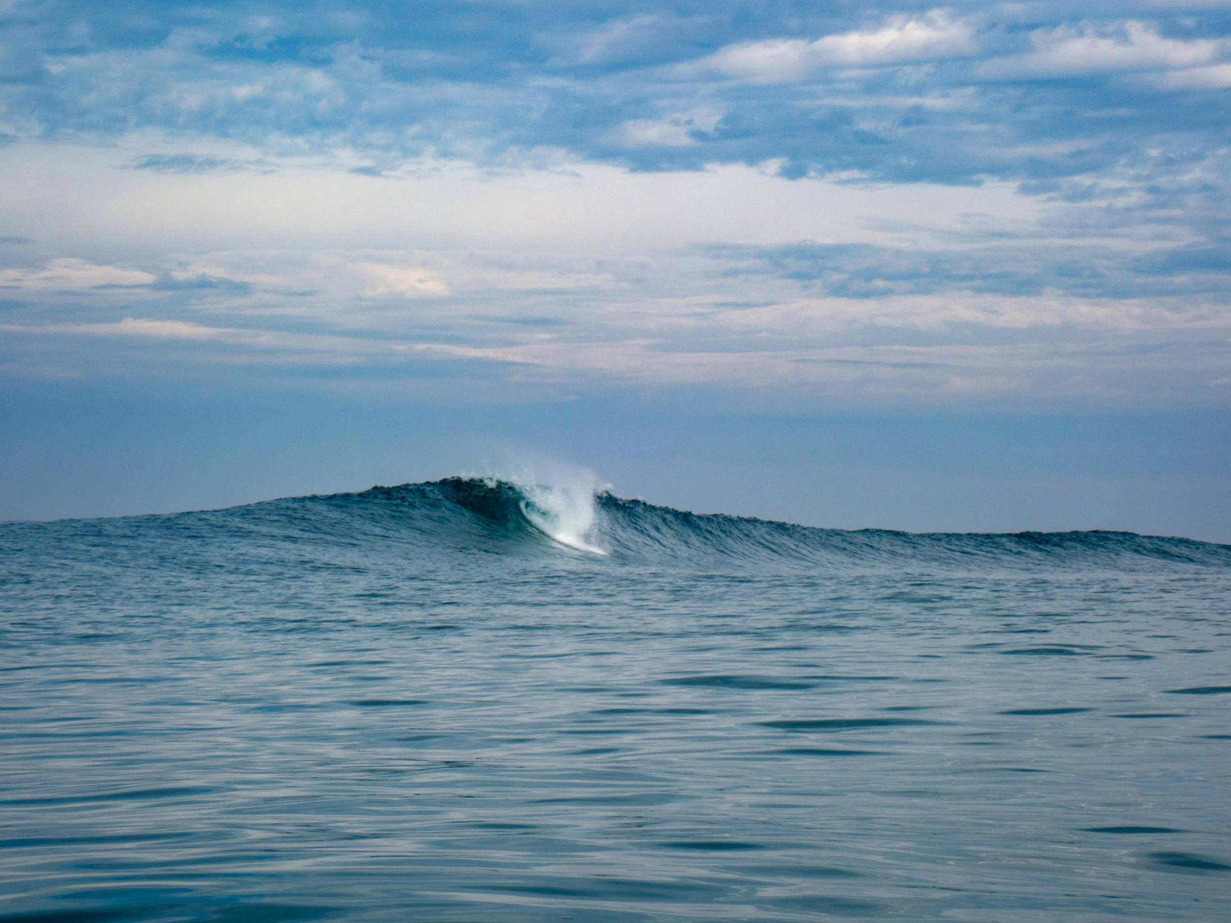 Ocean waves with a slight ripple and a distant cloud-filled sky.