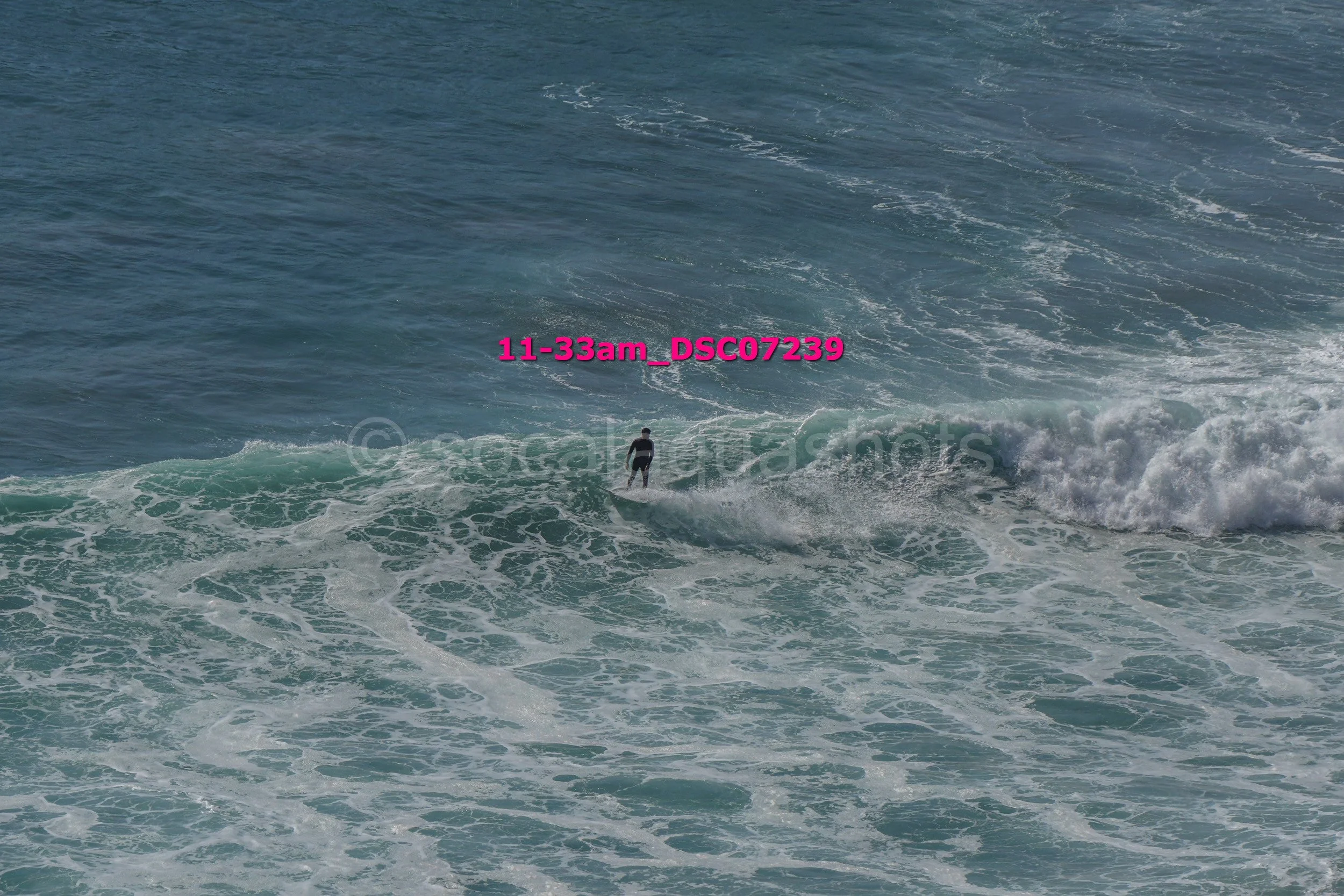 A person surfing on a wave in the ocean on a clear day.