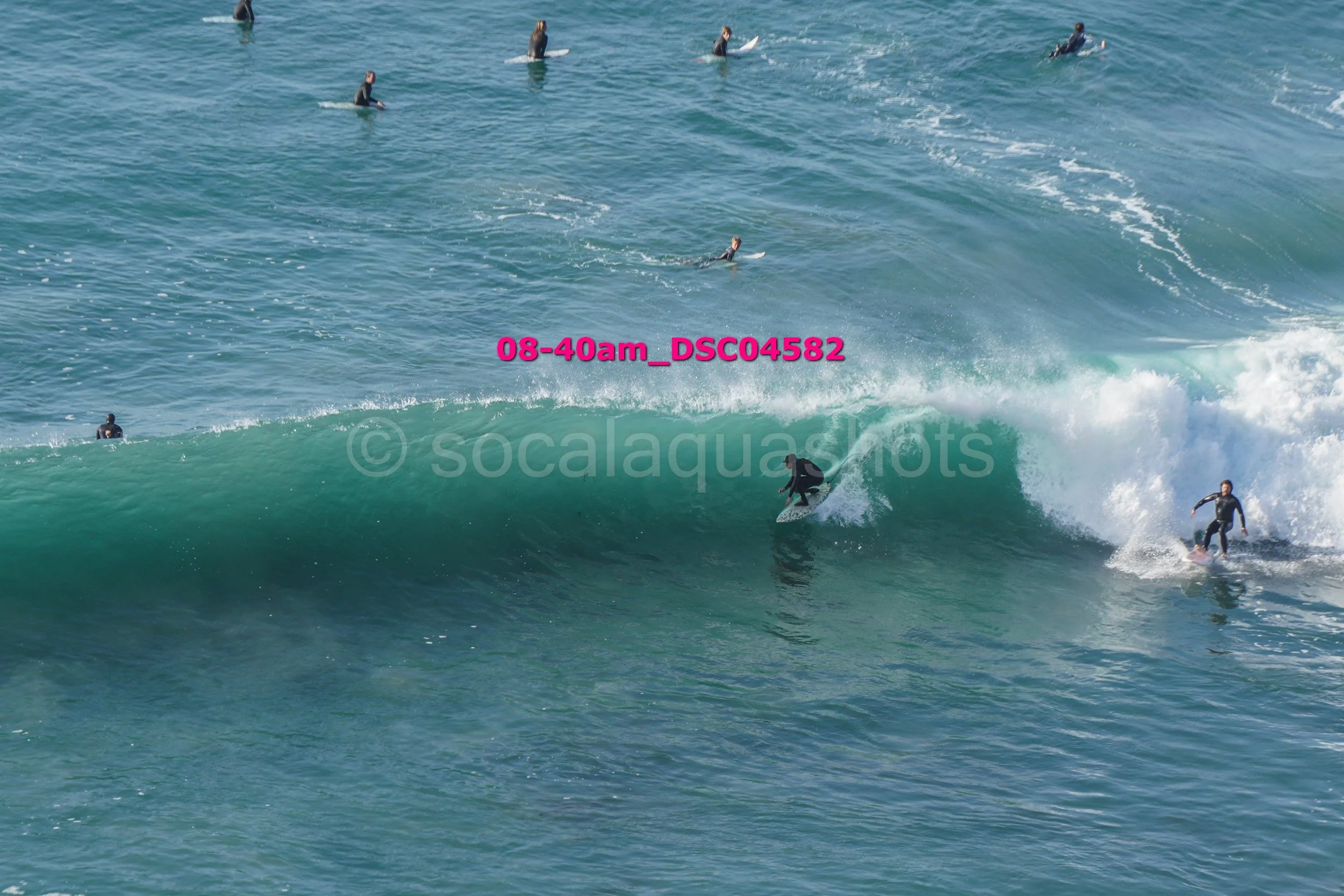 Multiple surfers riding and waiting for waves in the ocean.