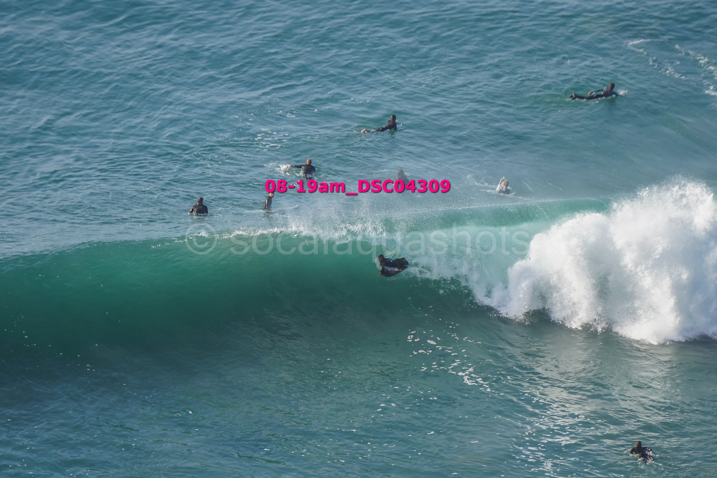 Surfers riding and waiting on large ocean waves during daylight.