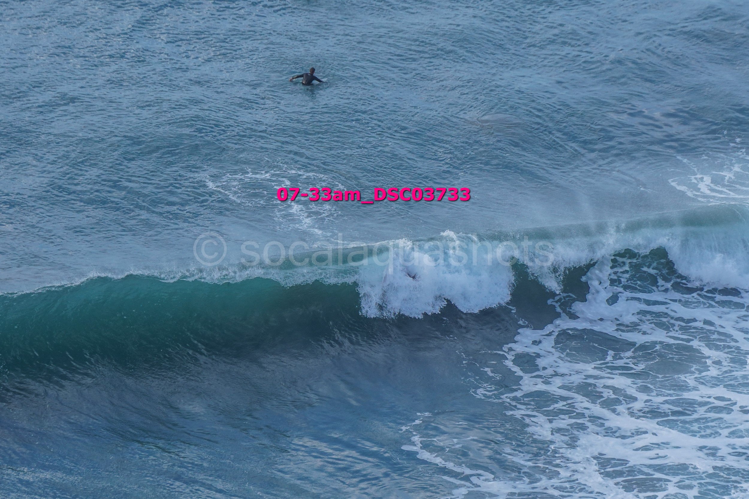 A person swimming in the ocean above a large wave.