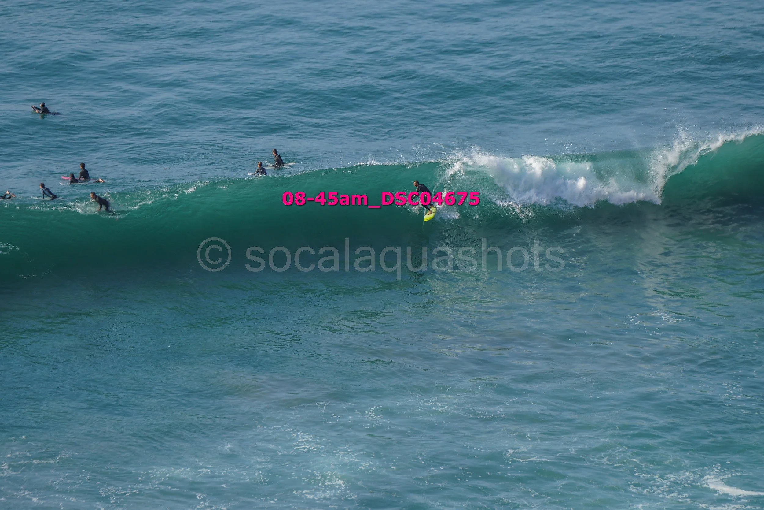 A group of people surfing on the ocean, with one surfer riding a wave and others waiting in the water.