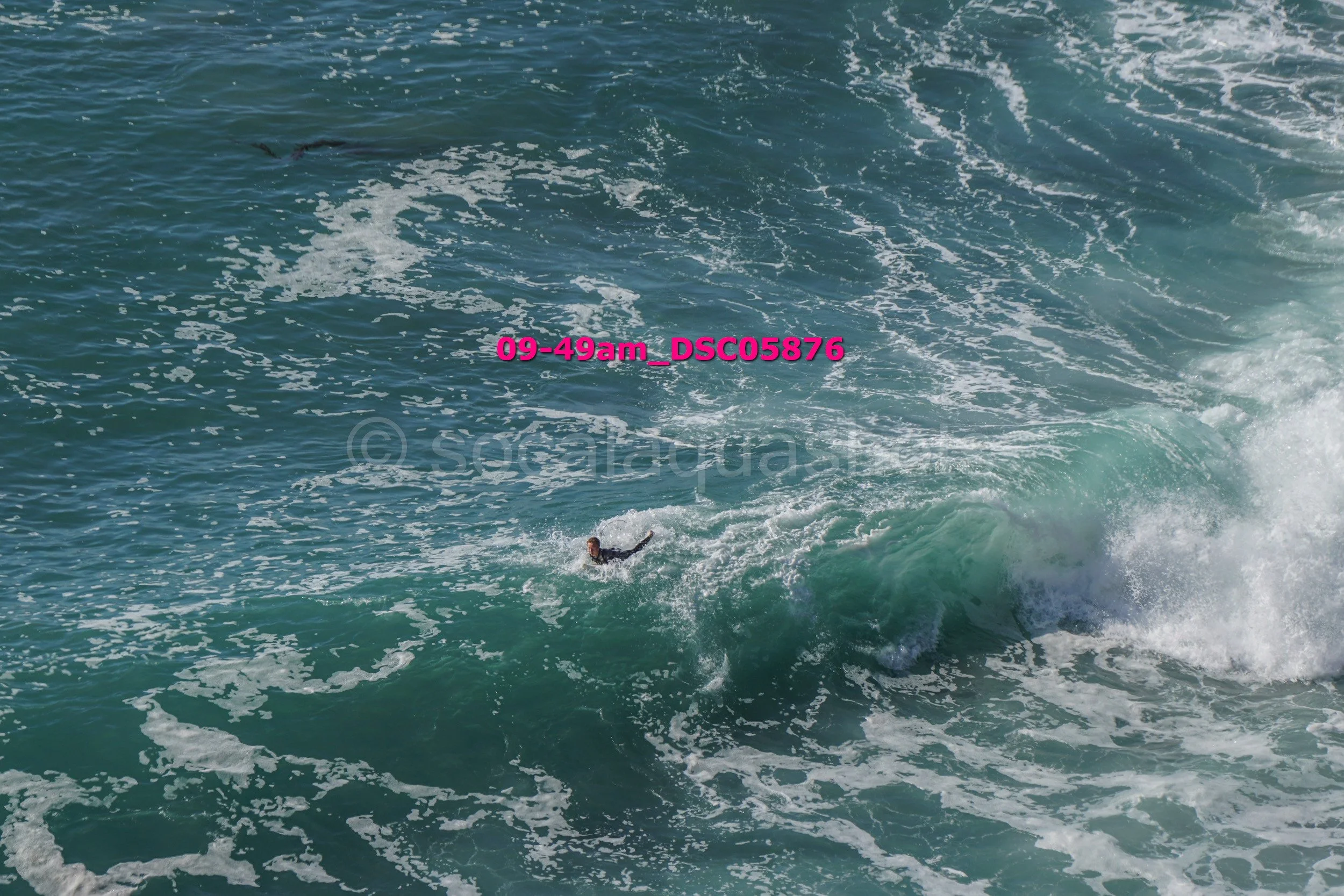A person in the ocean riding a large wave, with water splashing around.