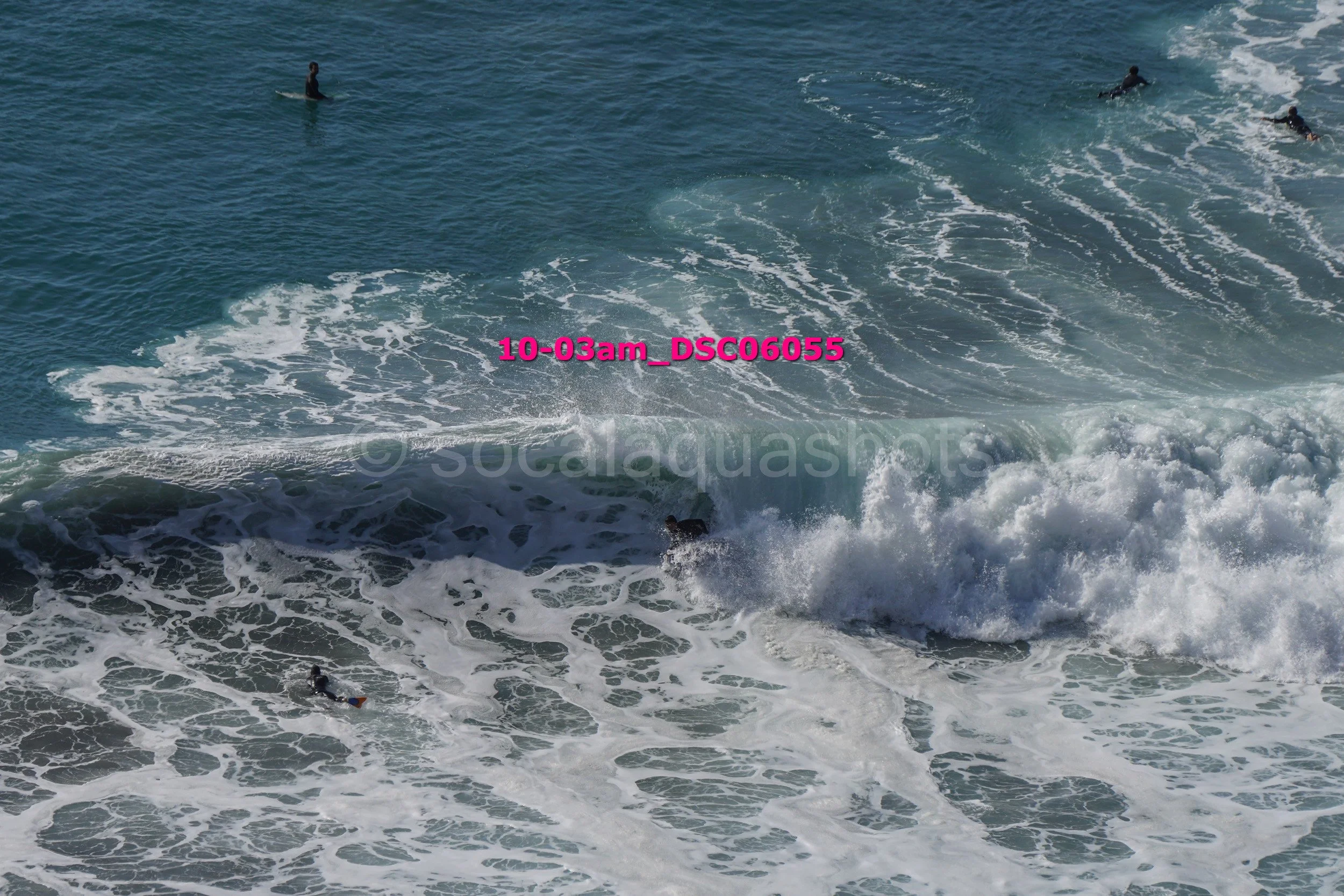 Surfers in the ocean riding and swimming in large waves.