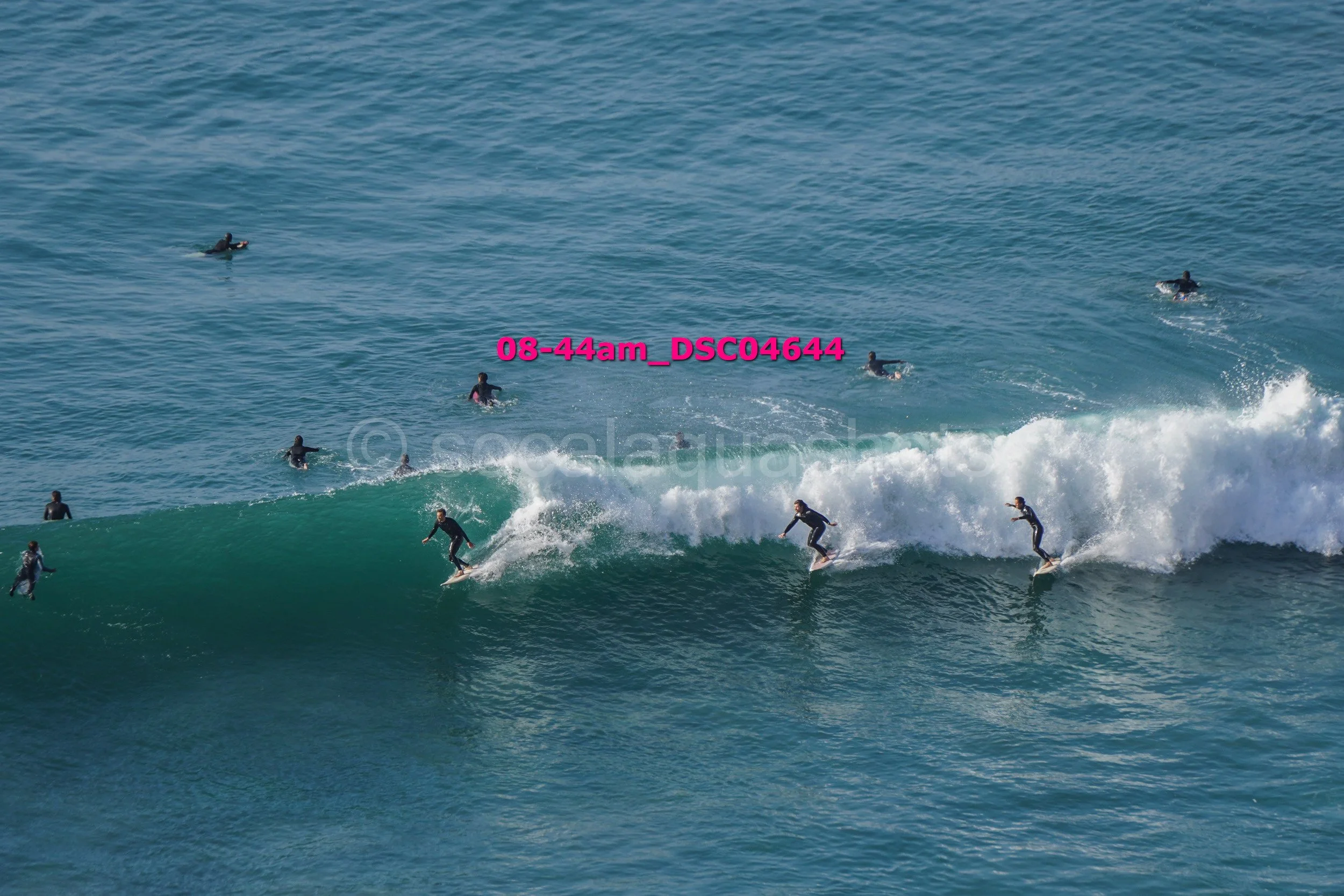 Multiple surfers riding waves in the ocean during daytime.