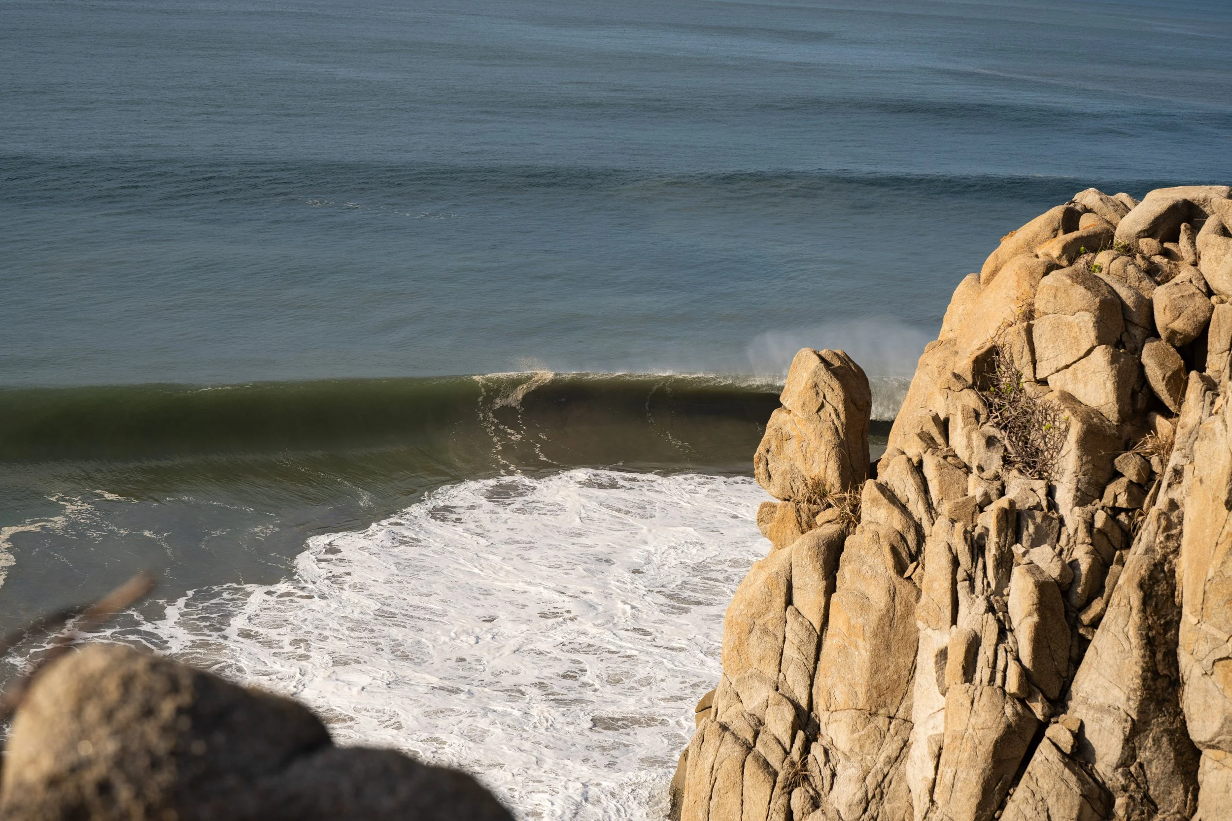 Rocks on the shoreline with ocean waves in the background.