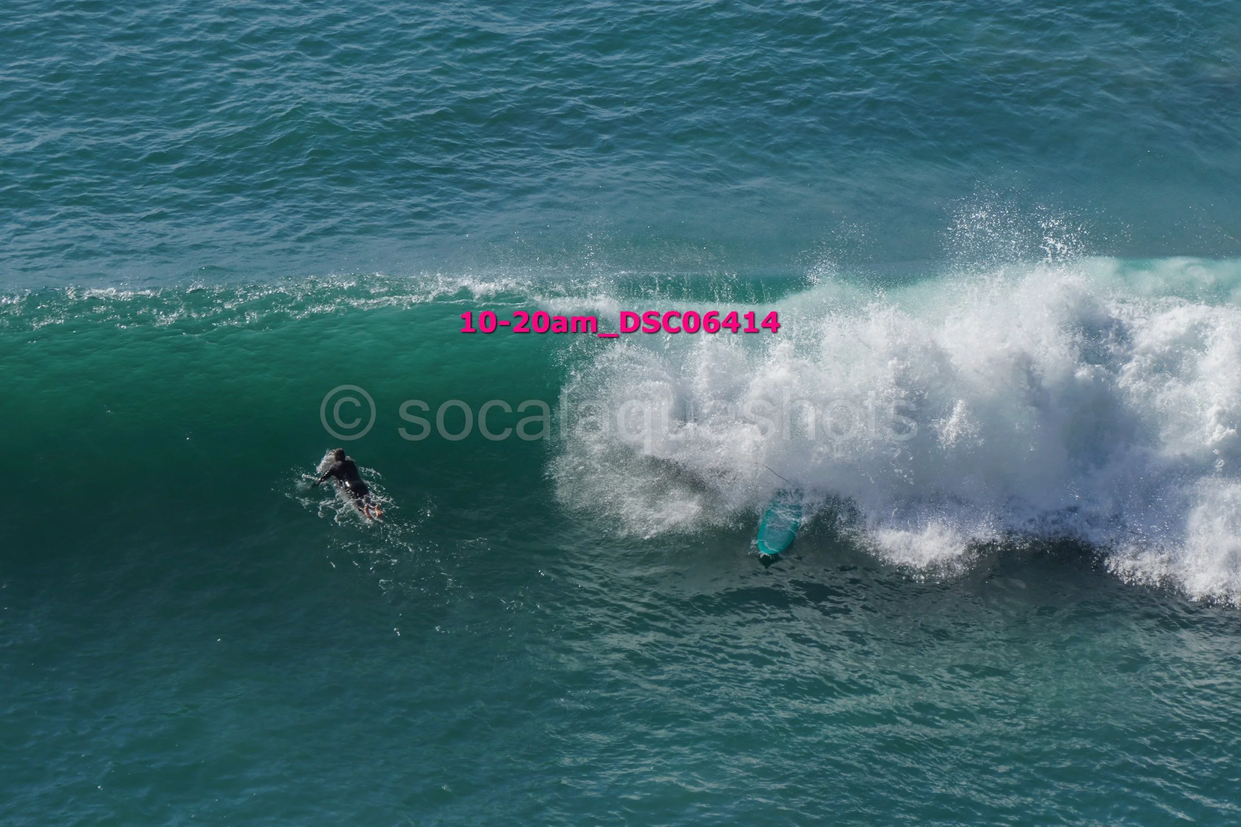 A person swimming away from a large breaking wave in the ocean.