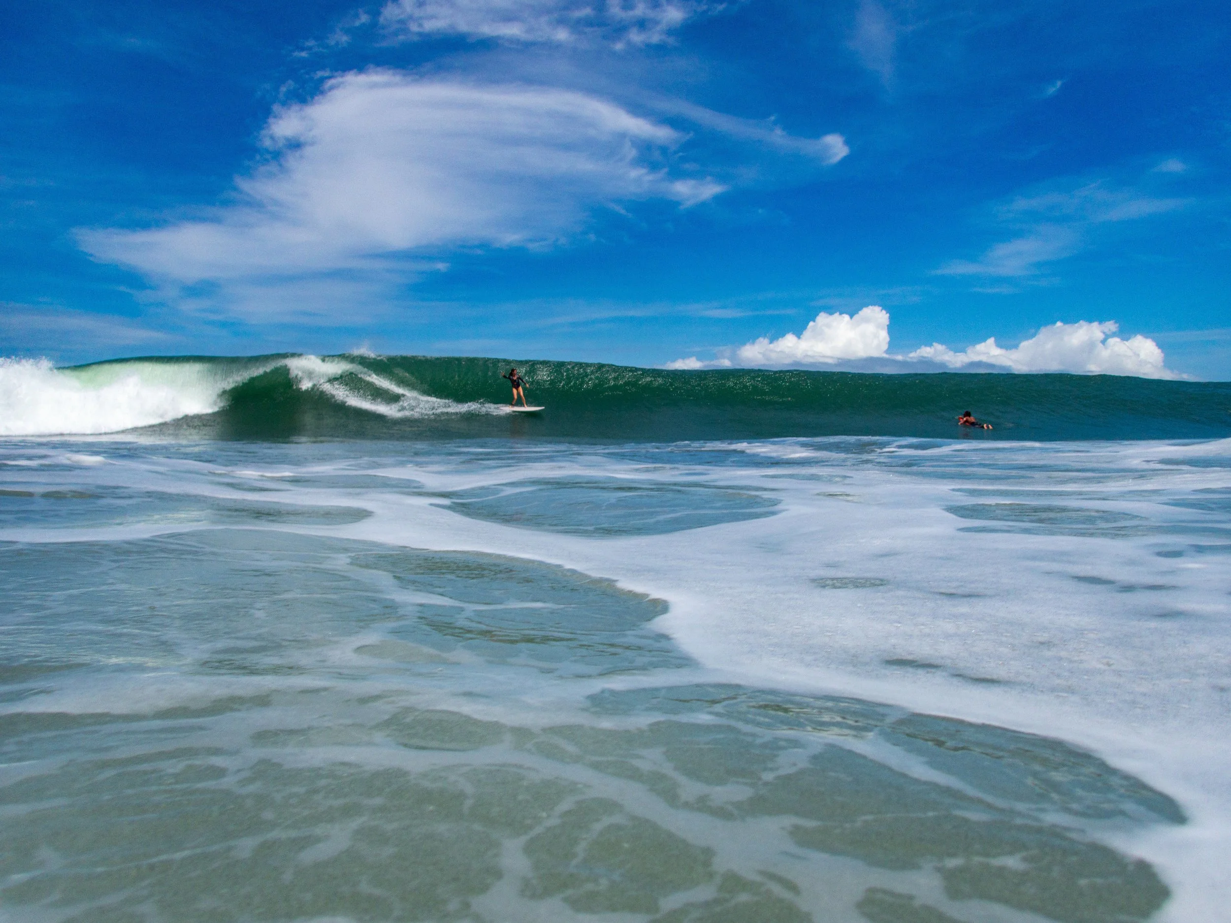 Surfer riding a wave in the ocean under a clear blue sky
