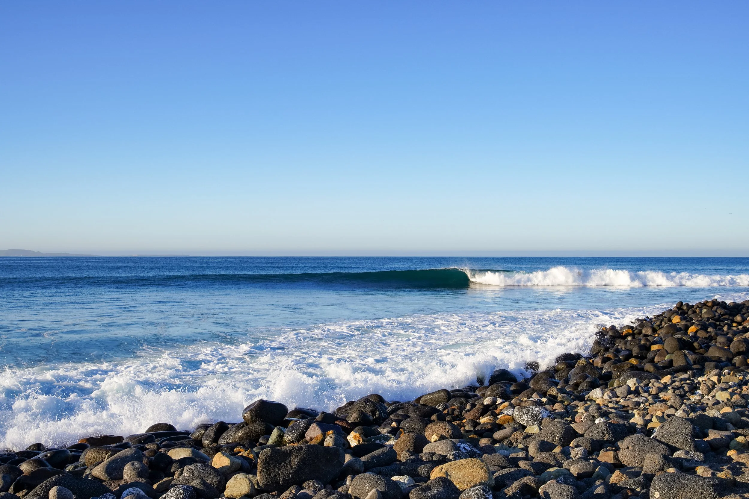 Rocky beach with ocean waves and clear blue sky