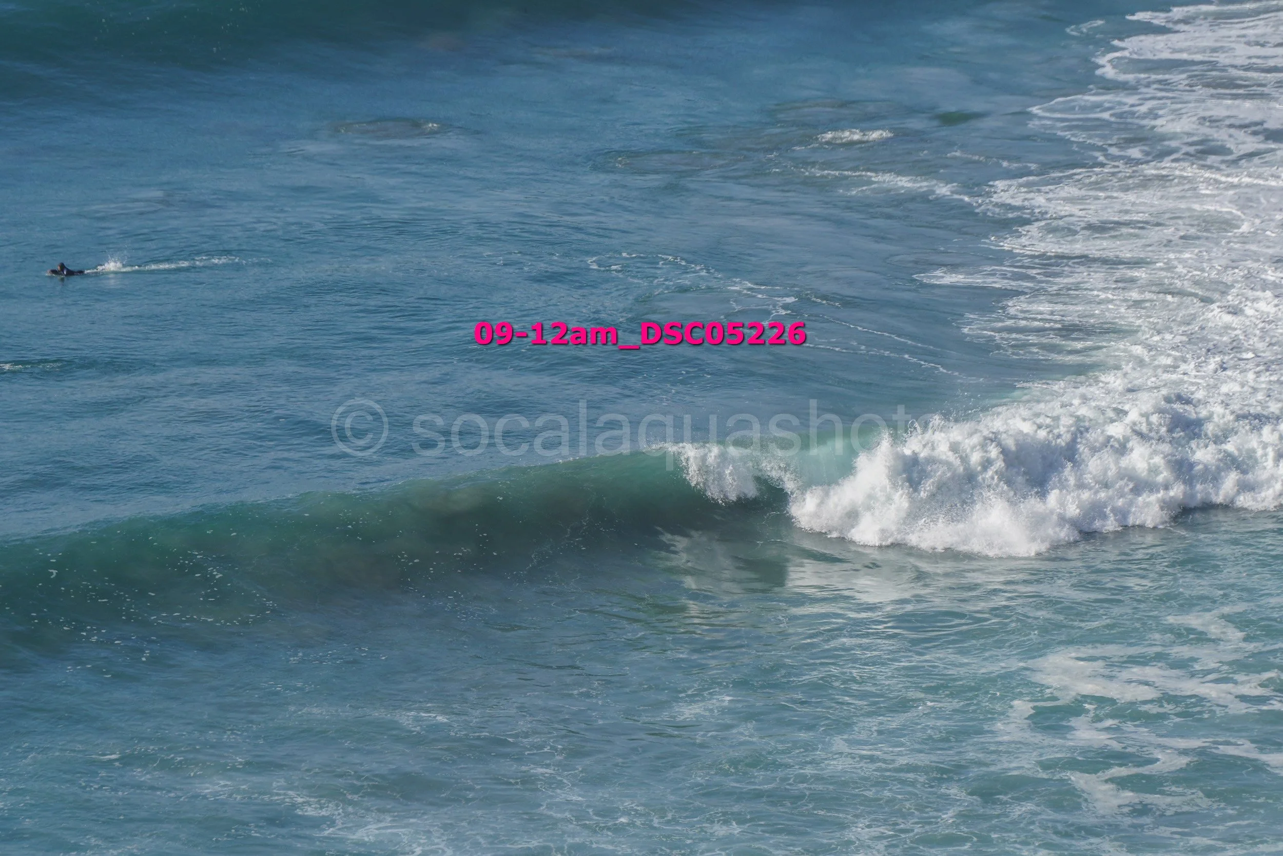 Ocean waves with a surfer riding a wave in the background.