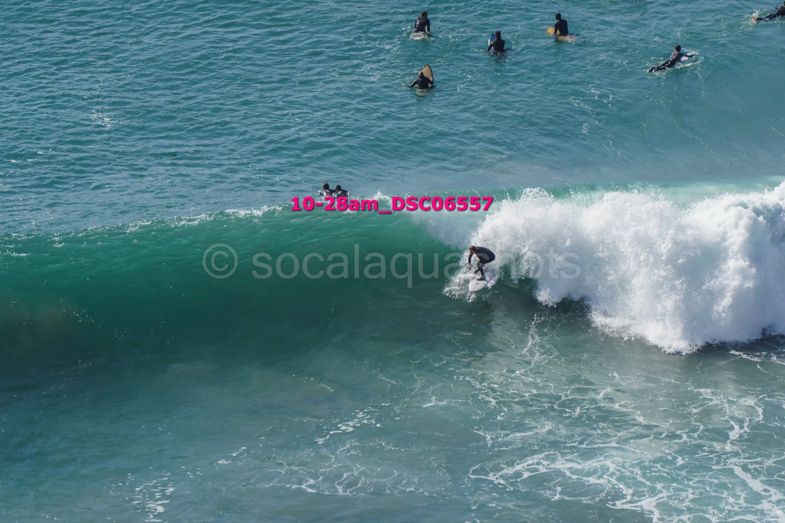 A surfer riding a wave with several people in the water watching from the background.