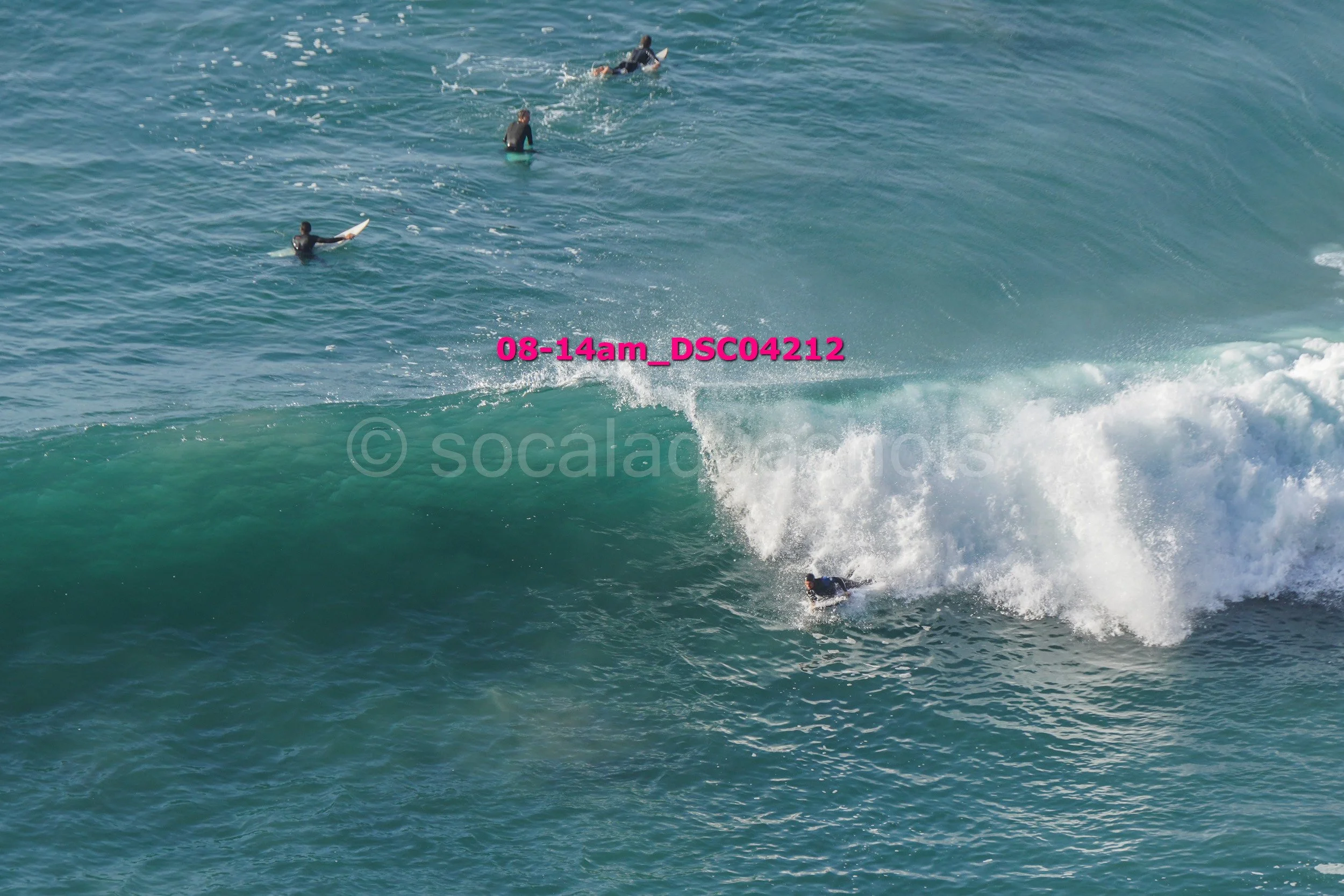 Surfers riding and waiting for waves in the ocean.