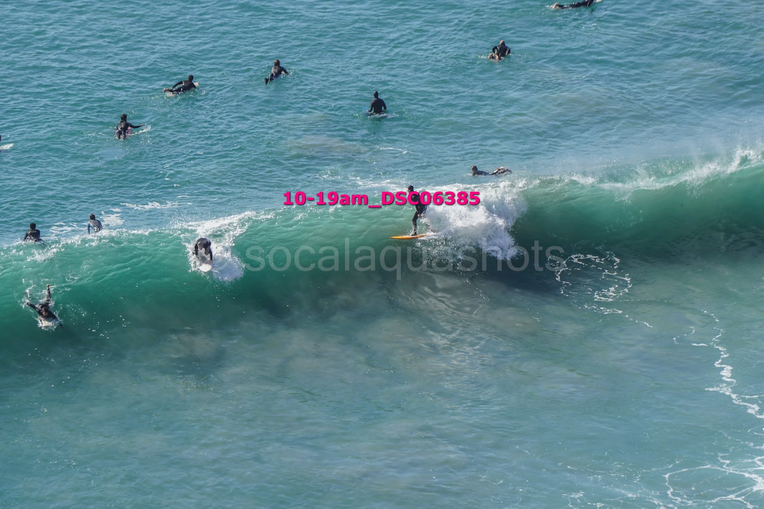 Surfers and swimmers in the ocean with one person surfing a wave.