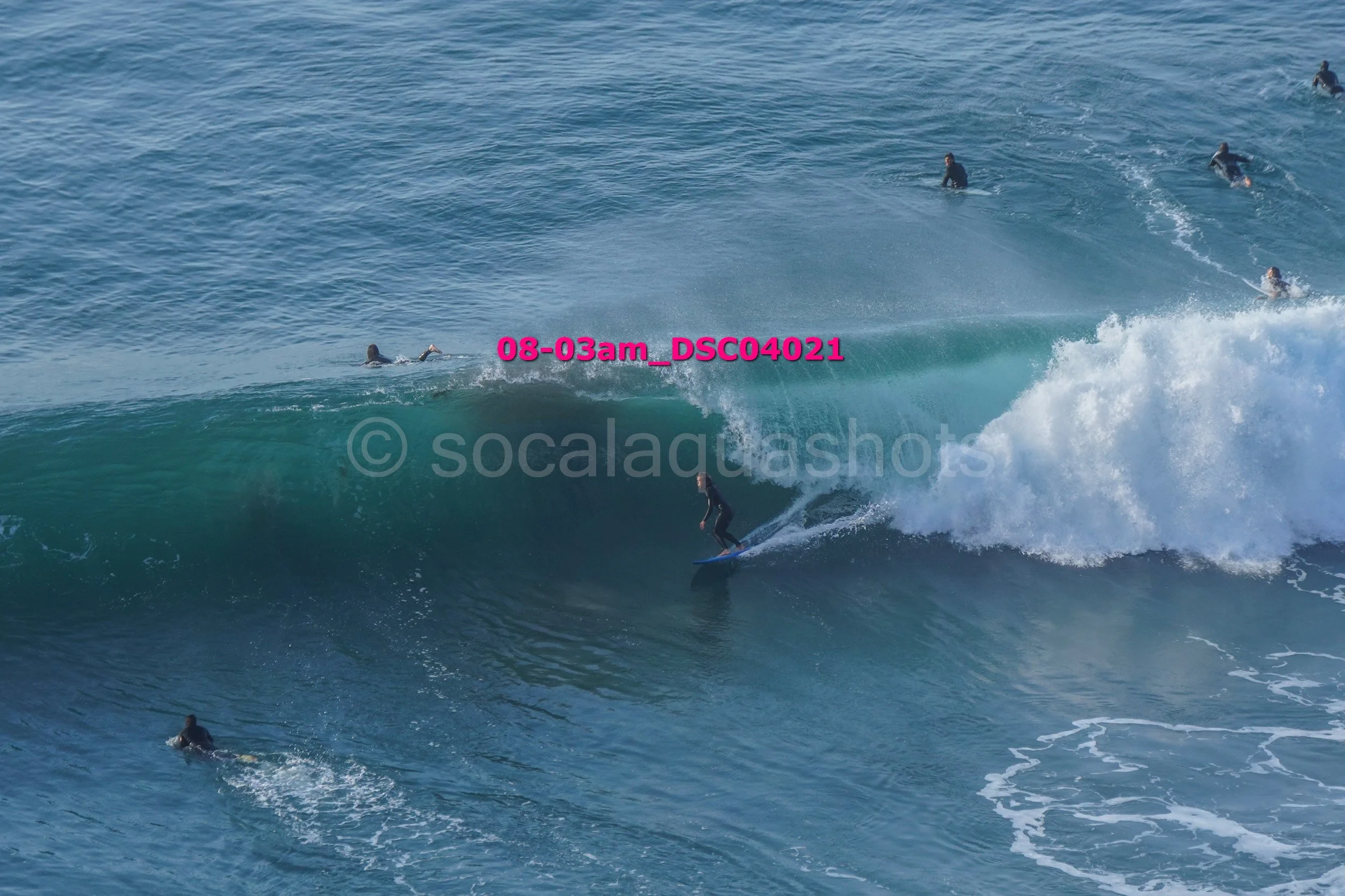 Surfer riding a wave with multiple surfers in the background in the ocean.