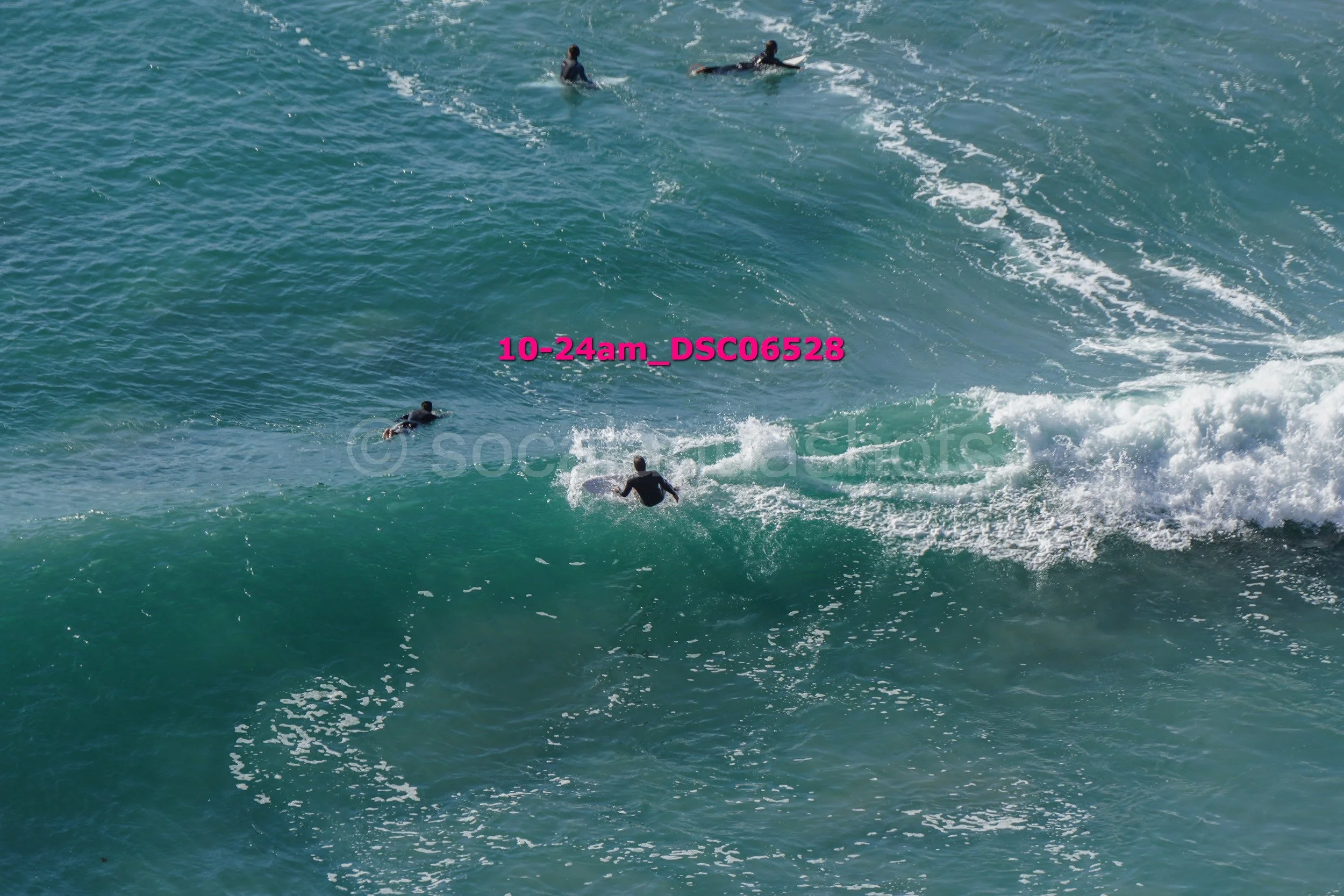 Four surfers riding and waiting for waves in the ocean.