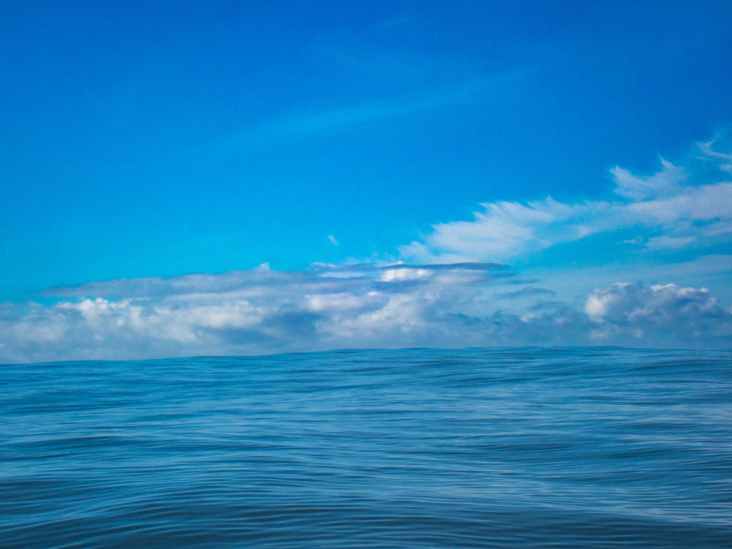 Calm ocean water with a partly cloudy sky in the background.