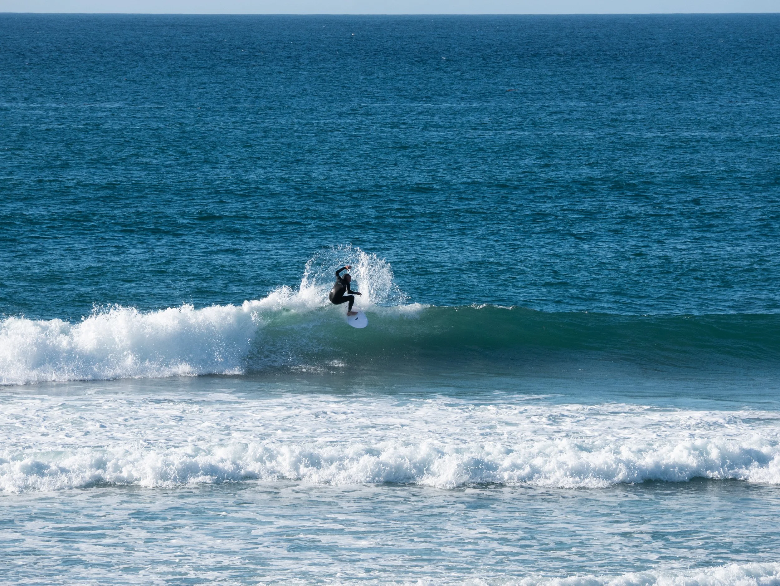 A person surfing on a wave in the ocean during the daytime.