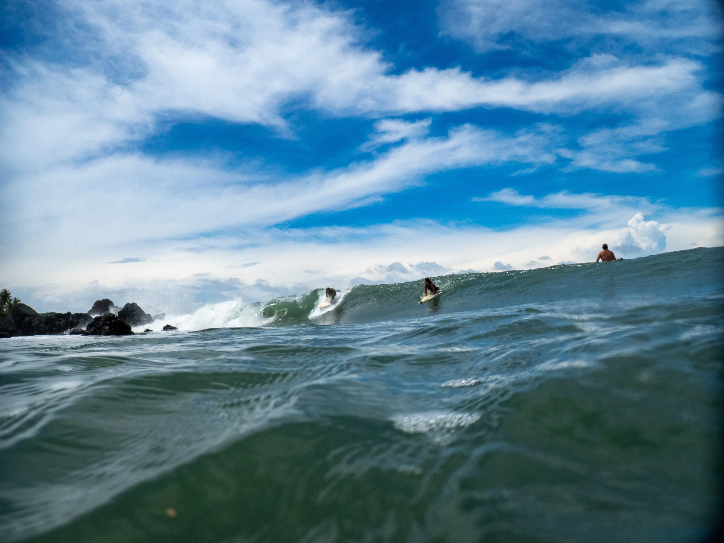 People surfing on ocean waves under a partly cloudy sky.
