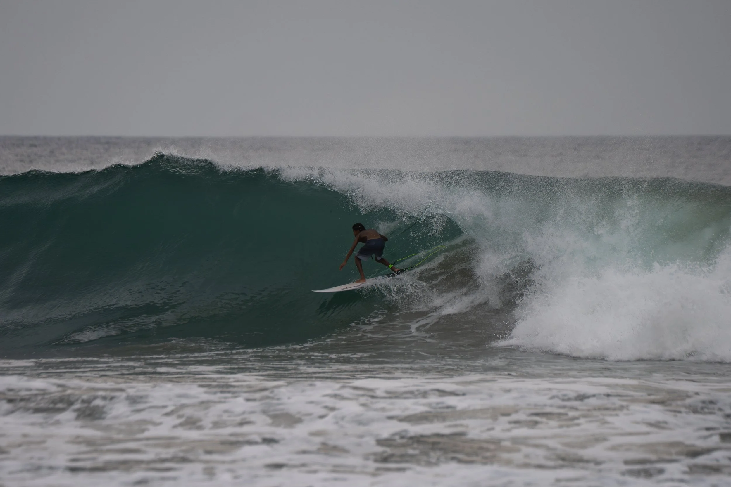A person surfing on a large wave in the ocean.