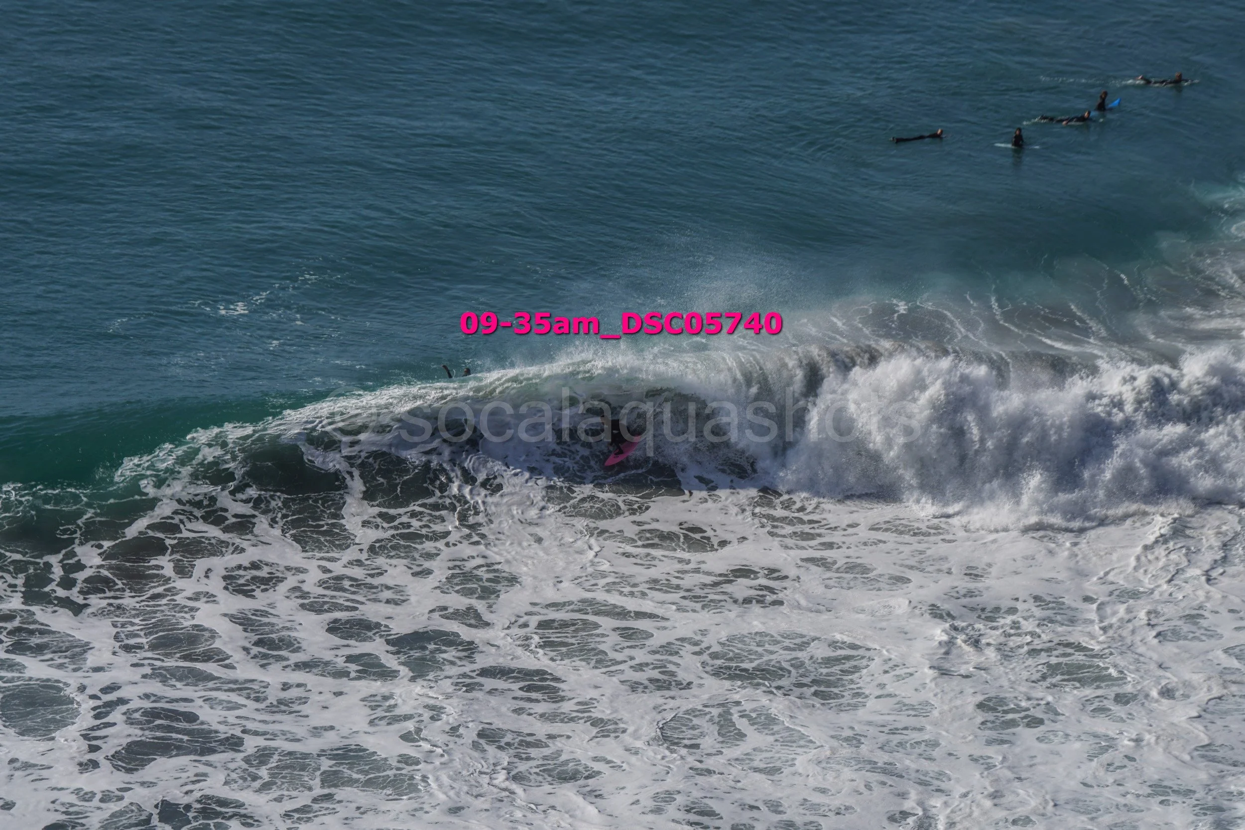 Surfers in the ocean, with one surfer partially submerged under a breaking wave.