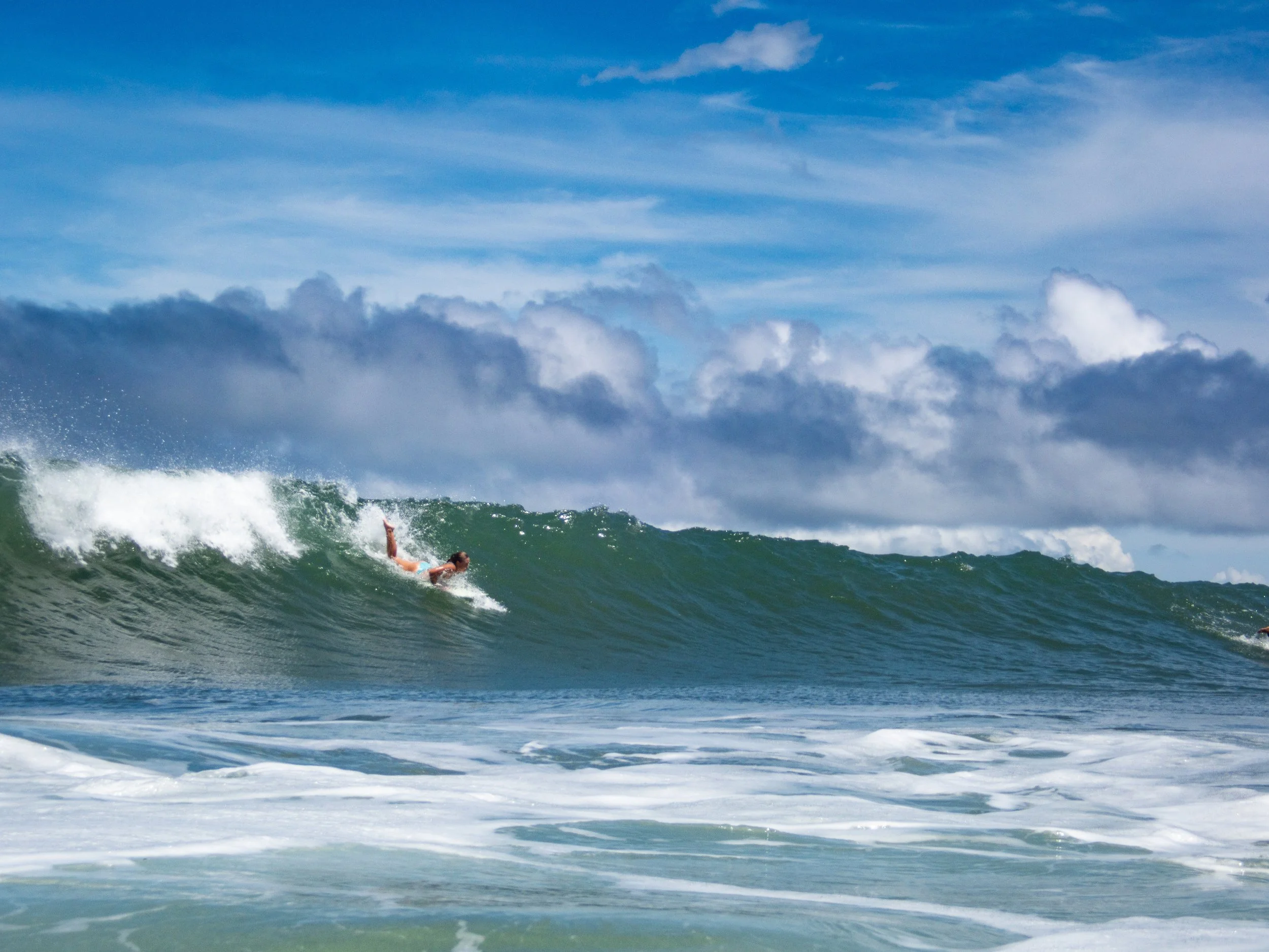 Surfer wiping out on a large ocean wave under a cloudy sky