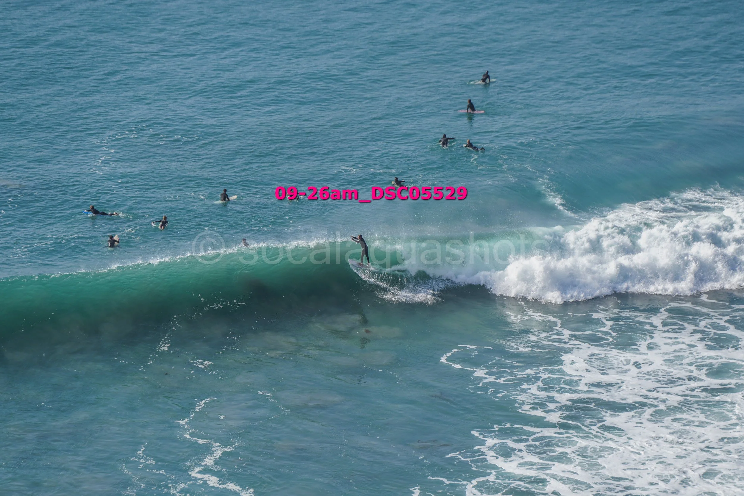 Surfer riding a wave with several surfers in the water in the background.
