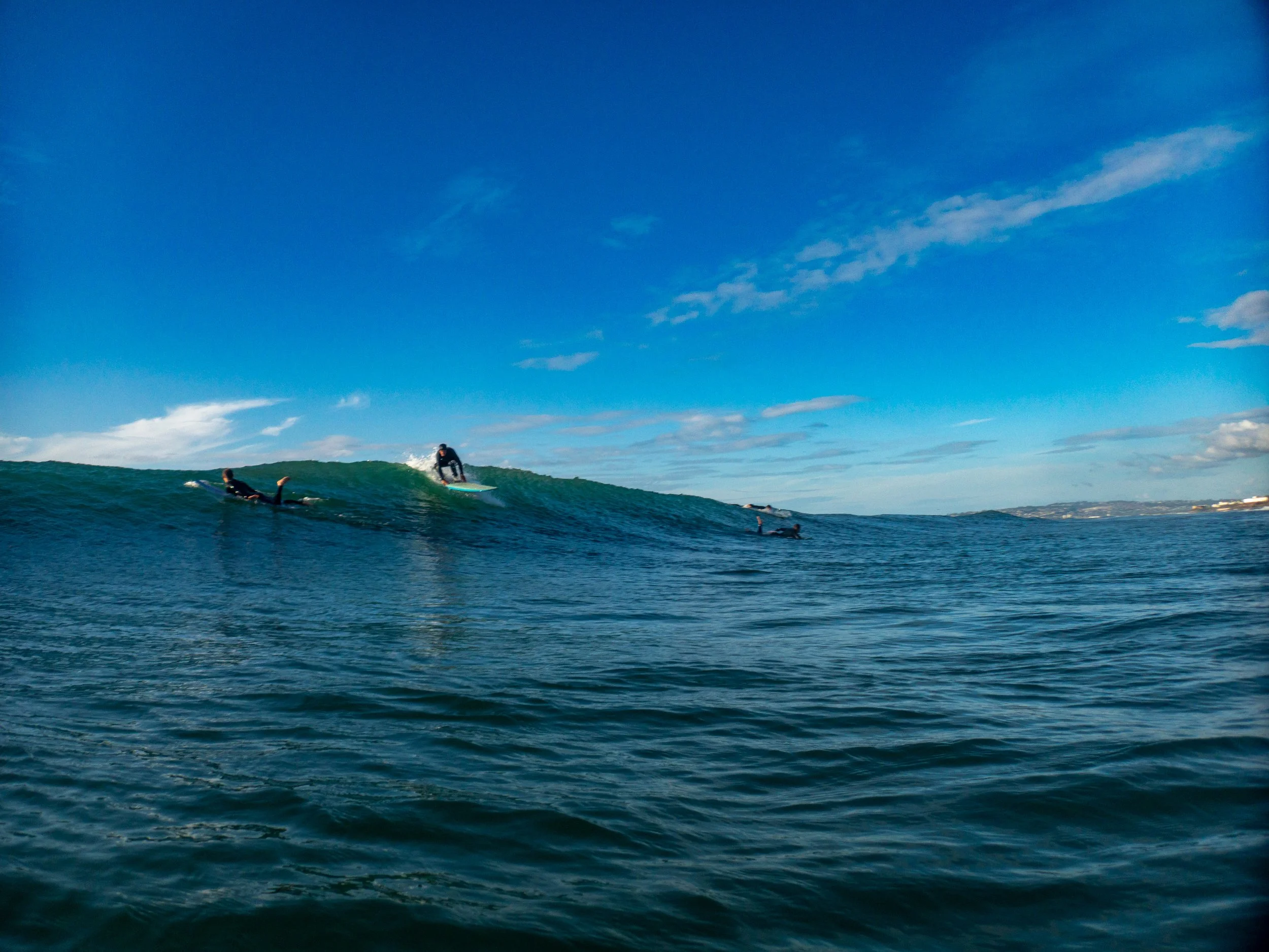 Surfers riding and waiting for waves in the ocean on a sunny day.
