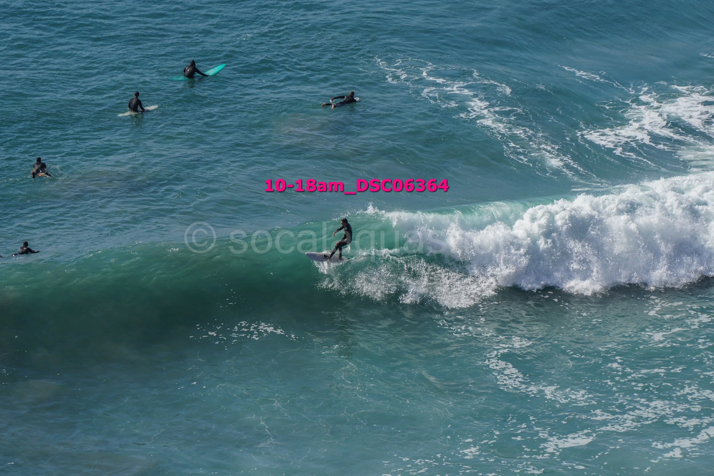 People surfing on the ocean waves, some riding surfboards and others paddling with surfboards, during daytime.