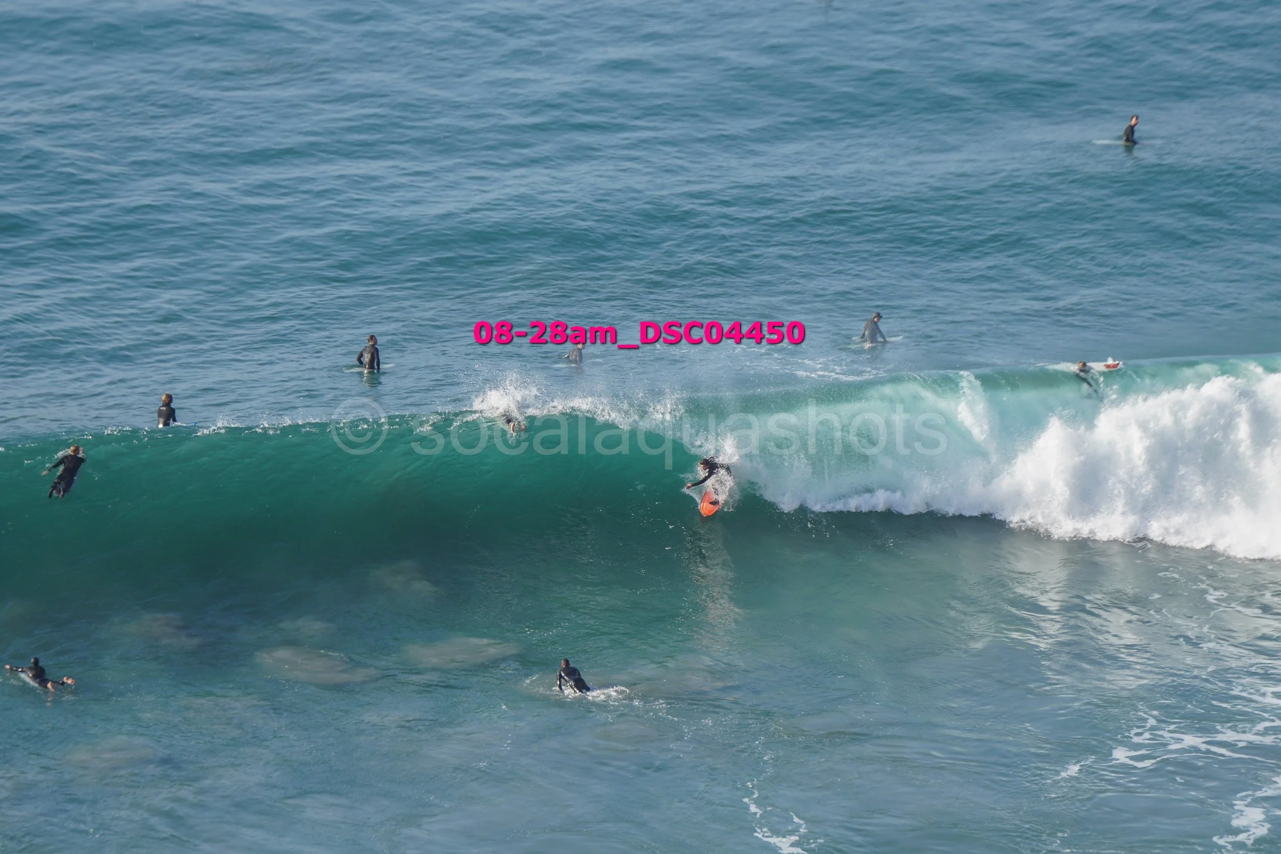 Surfer riding a wave with several surfers in the water around.