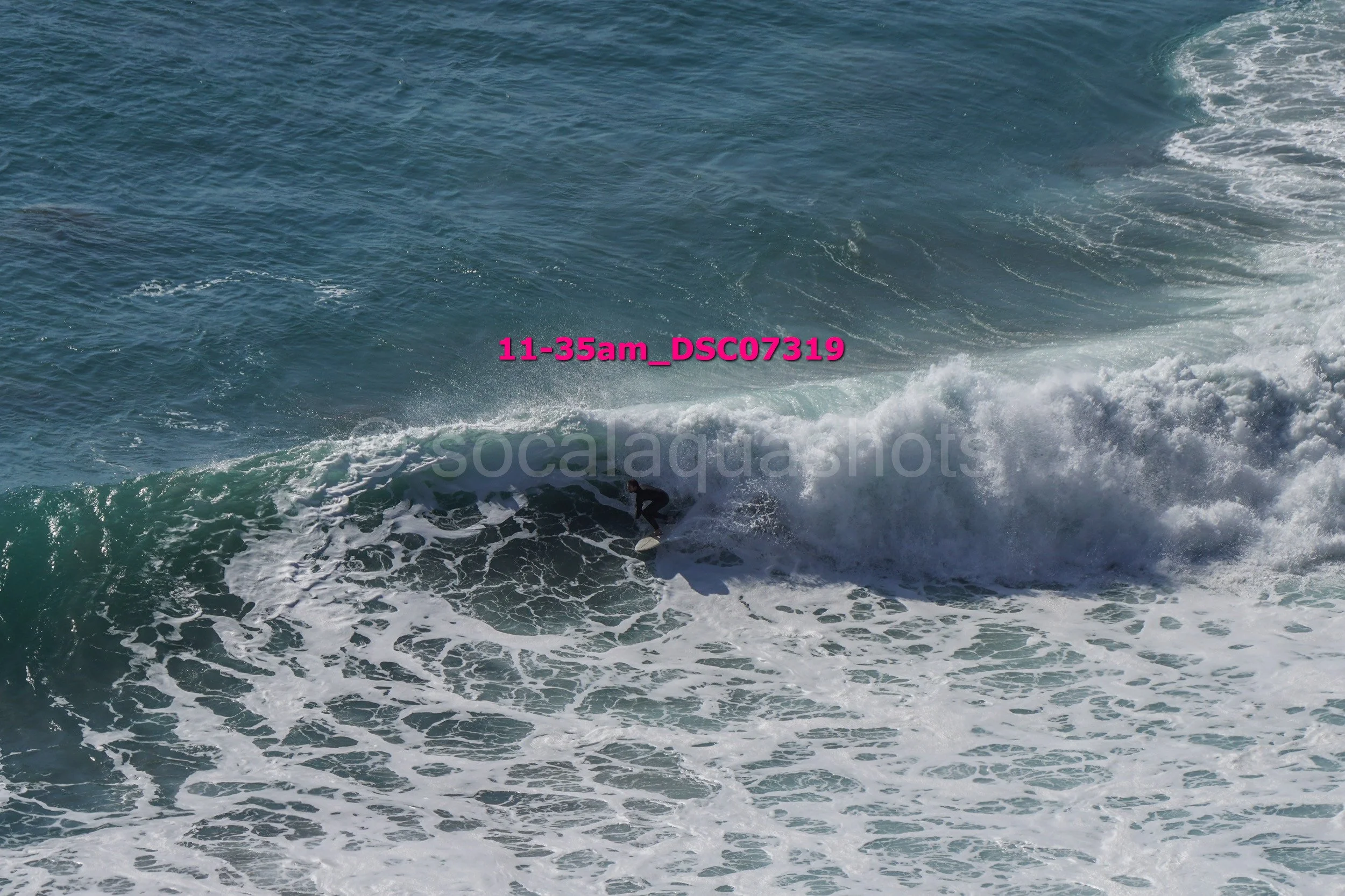 A person surfing on a wave in the ocean, with visible white foam and water spray