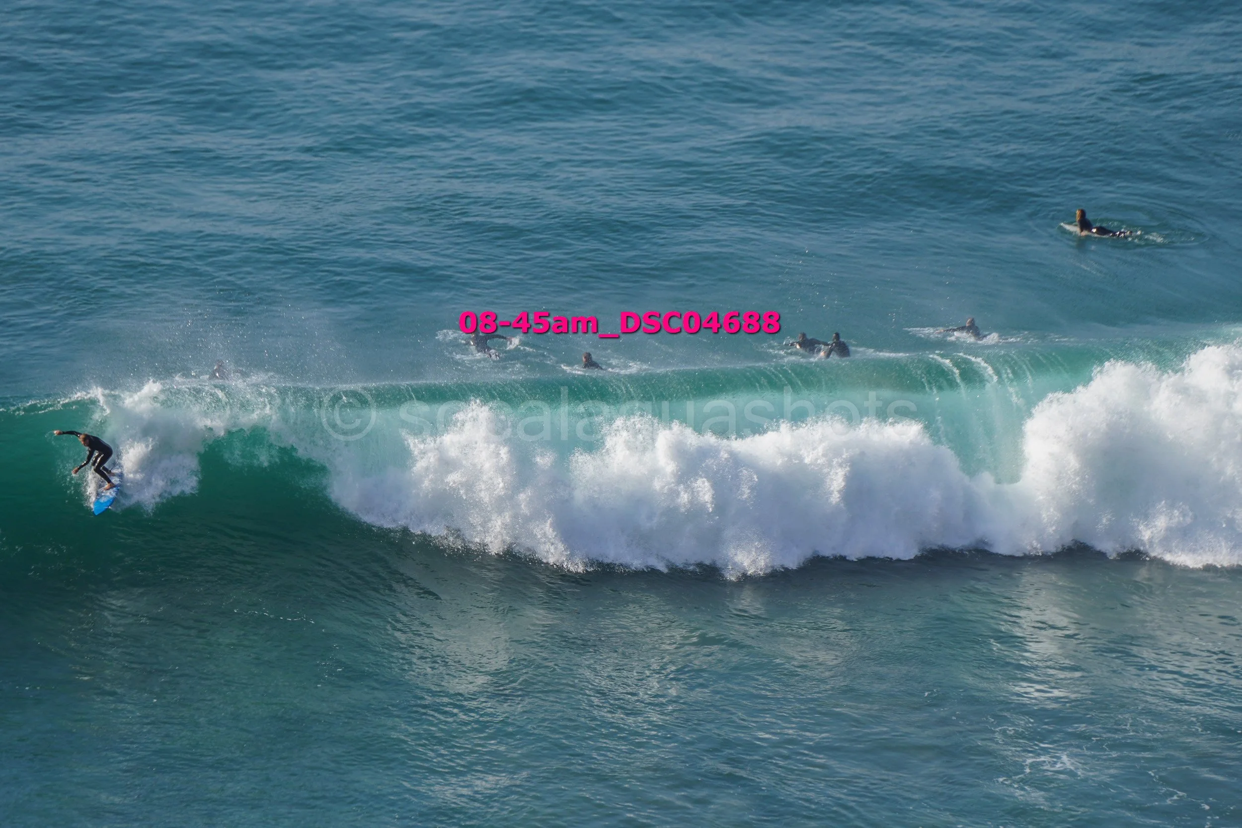 Surfer riding a wave while several surfers wait in the ocean, with text overlay reading '08-45am_DSC04688'