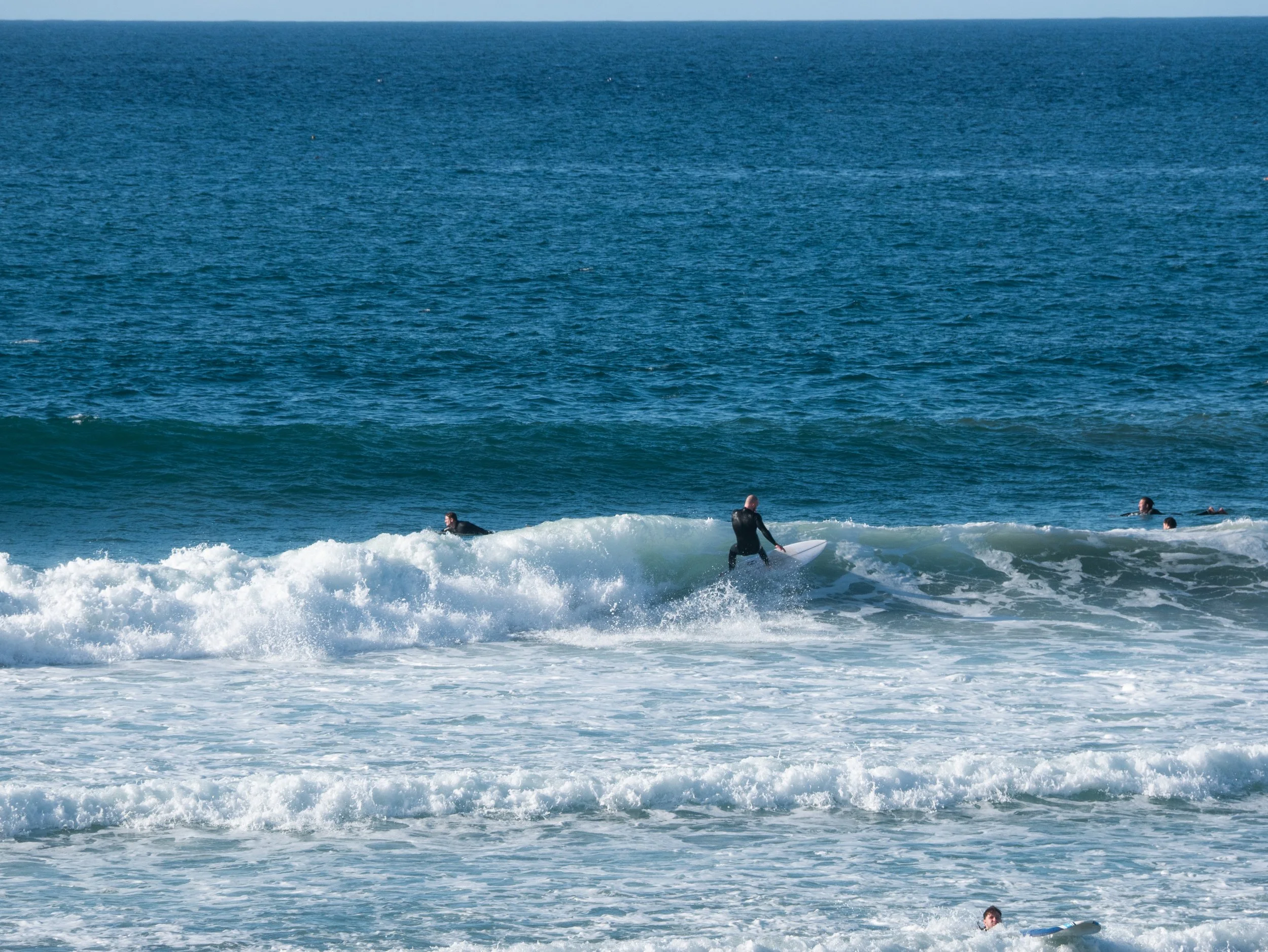 People surfing in the ocean with some waves visible.