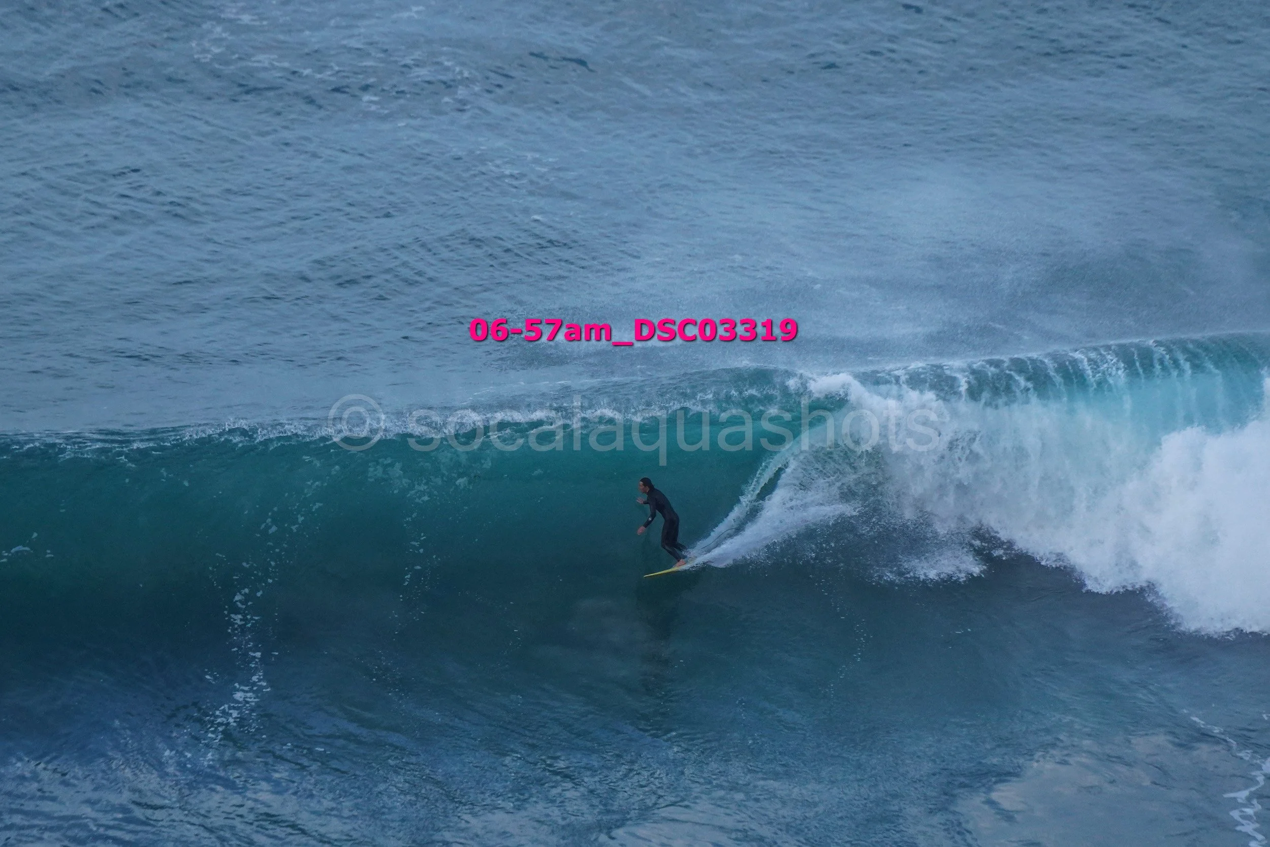 A person surfing on a large blue wave in the ocean.