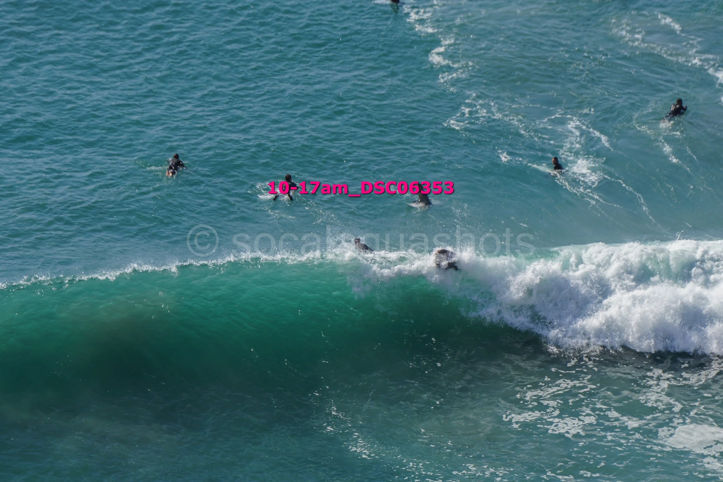 A group of people surfing on the ocean waves with some riding the wave and others paddling.