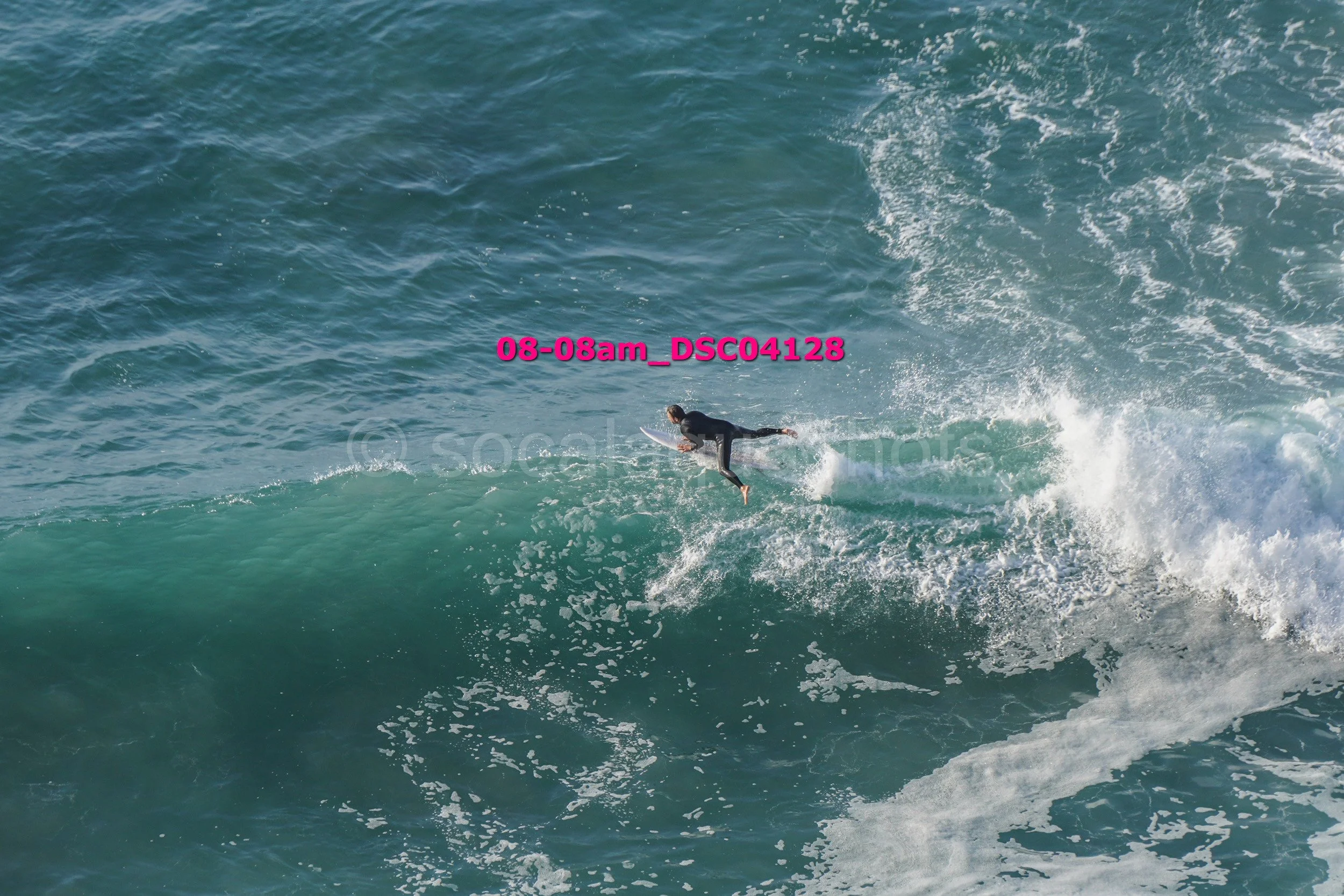 A surfer riding a wave in the ocean, wearing a wetsuit and holding a surfboard.
