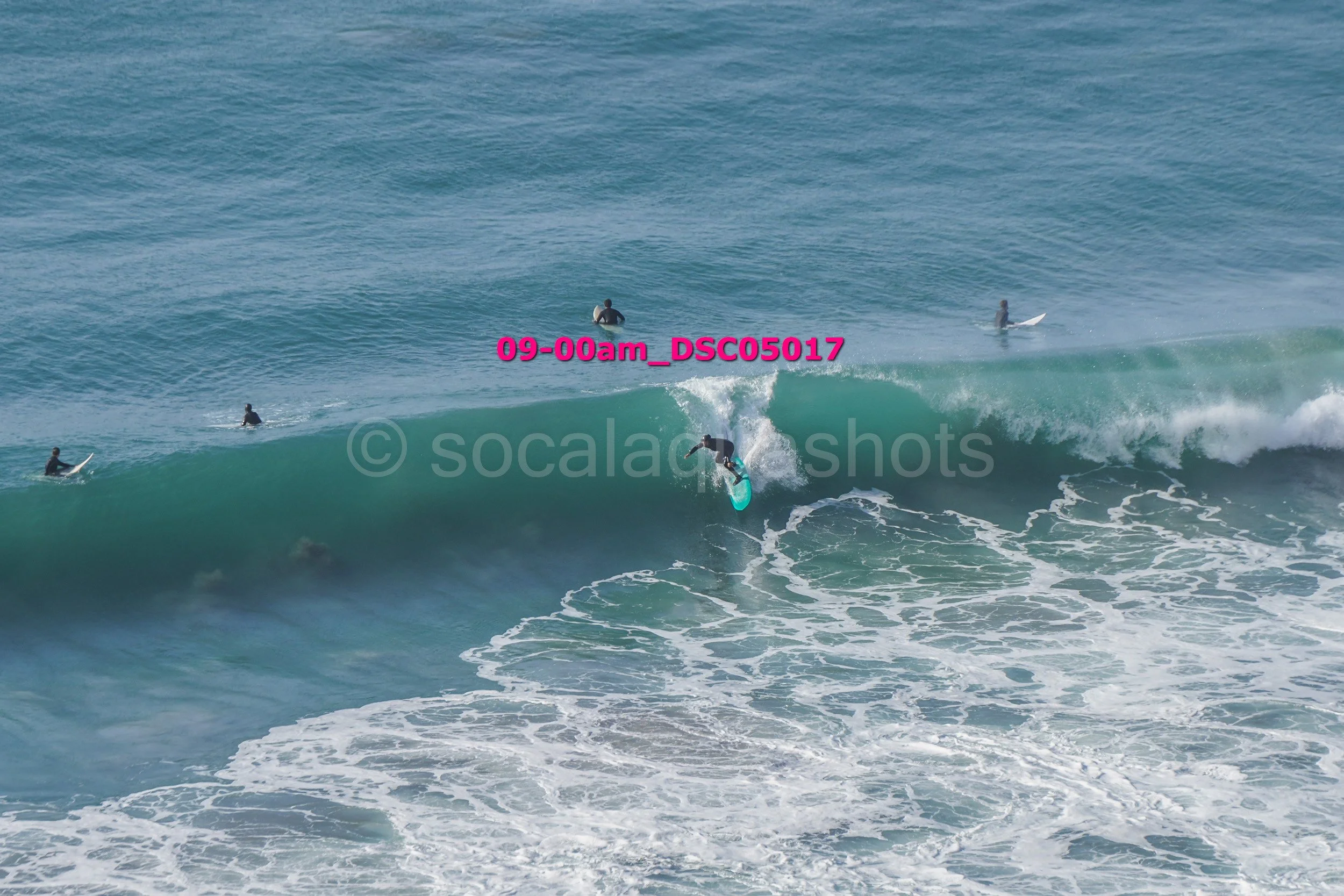Surfer riding a wave with other surfers waiting in the water.