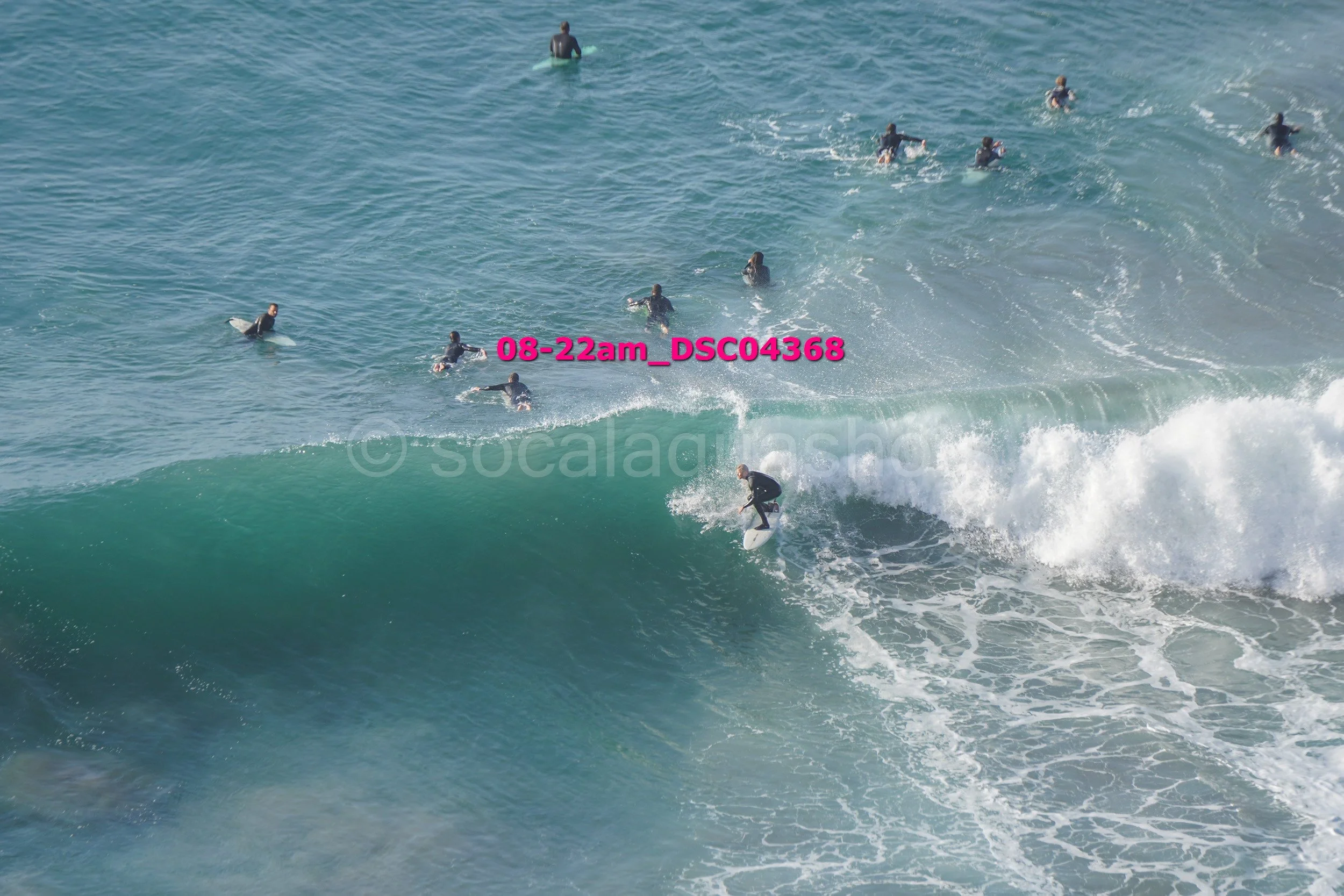 Surfer riding a wave with several people in the water watching.