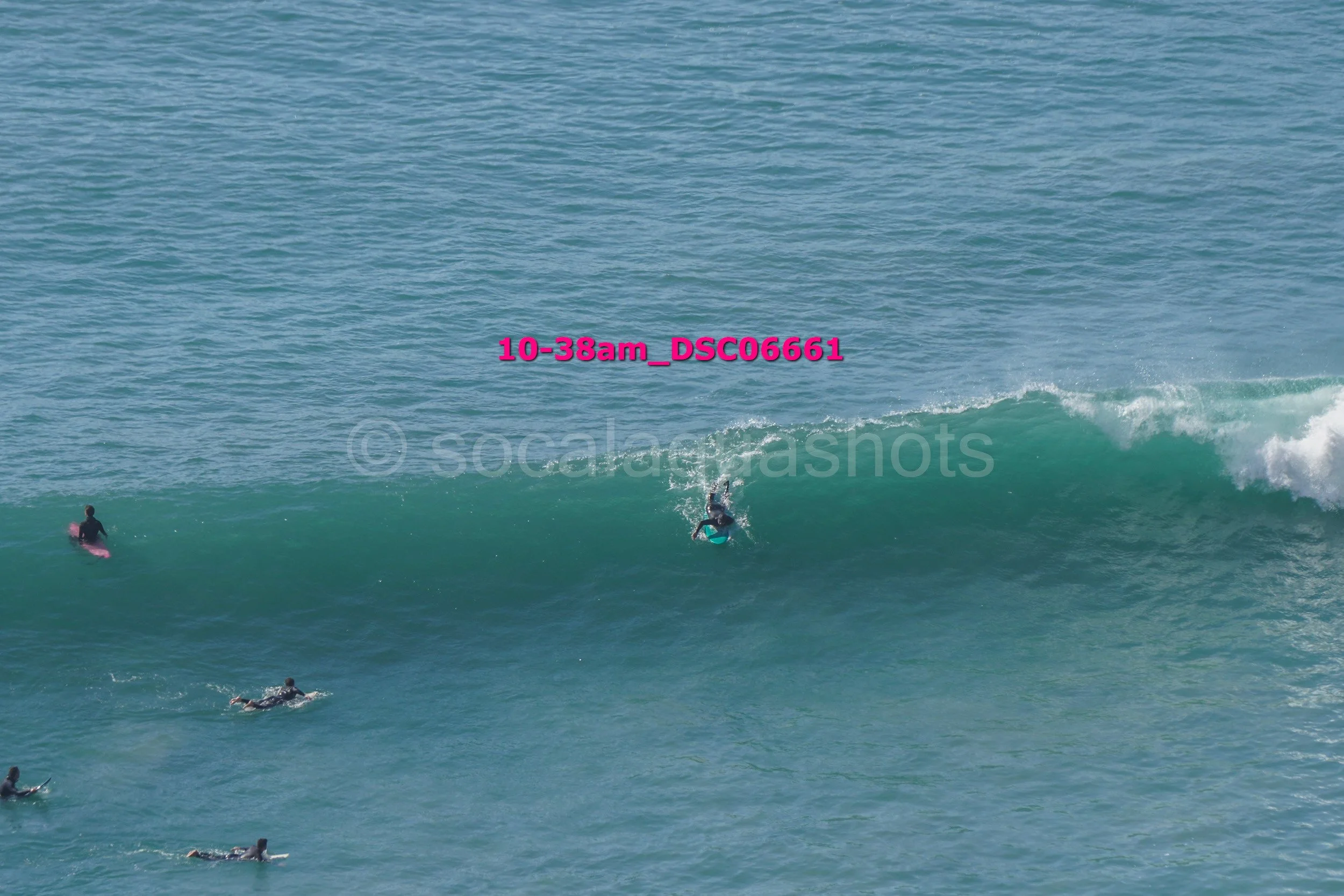 Surfers in wetsuits on surfboards riding and paddling in the ocean waves.