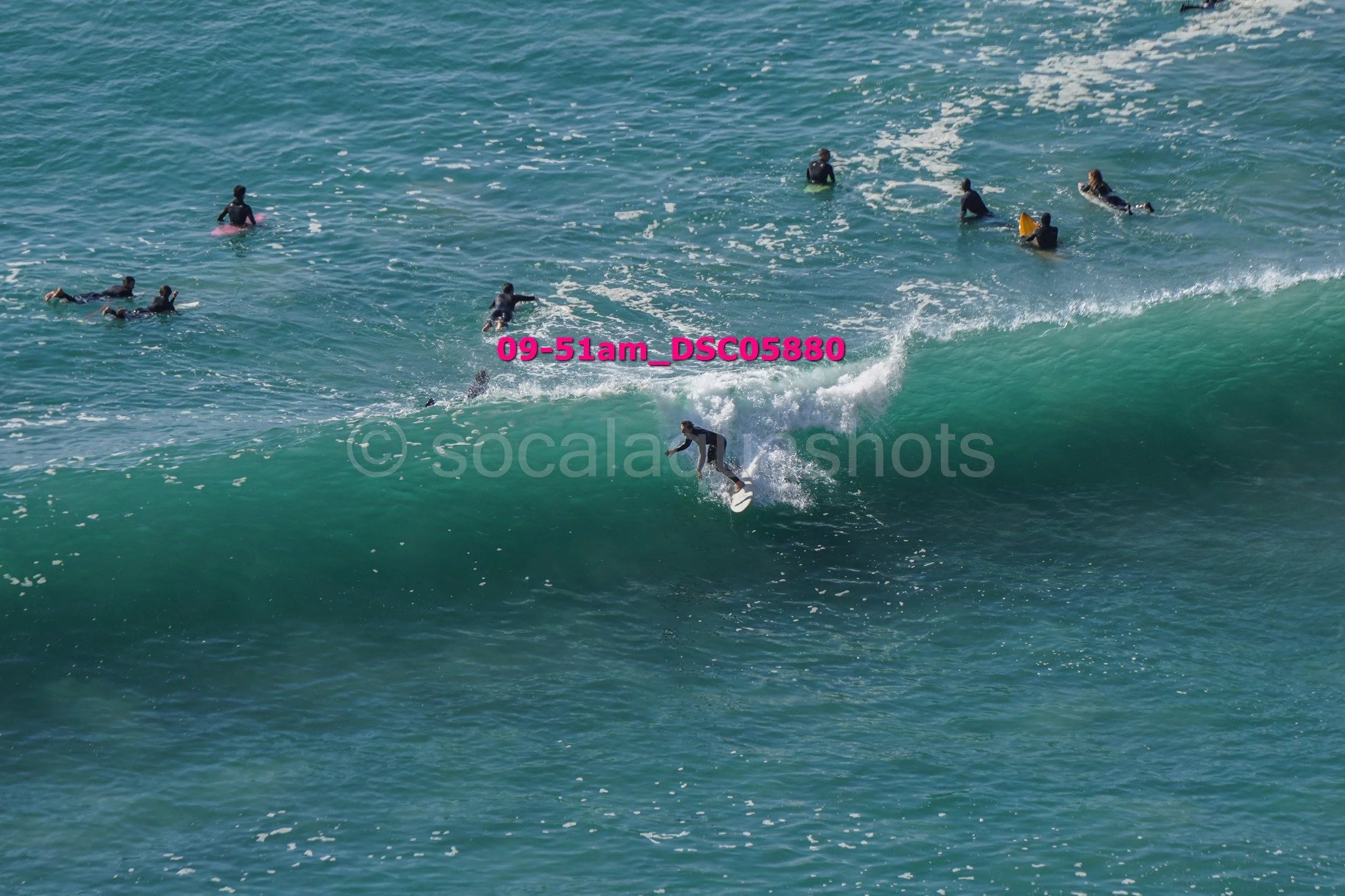 Surfer riding a wave with several surfers in the ocean nearby.