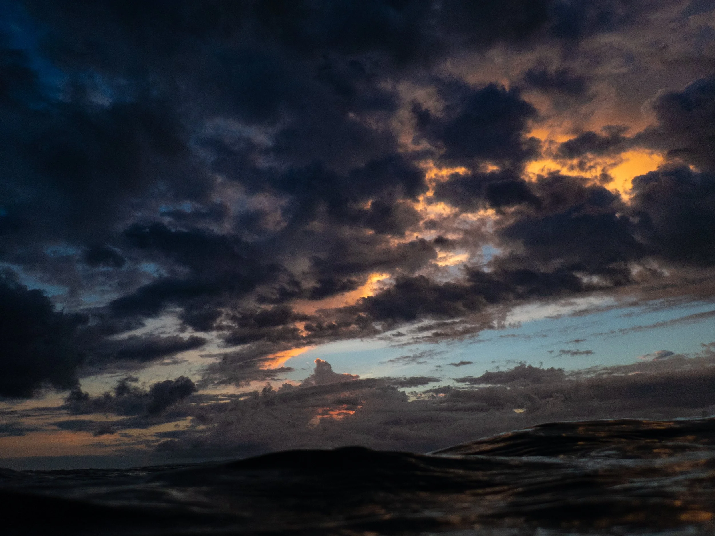 Dark clouds in a sky during sunset with a faint orange glow.